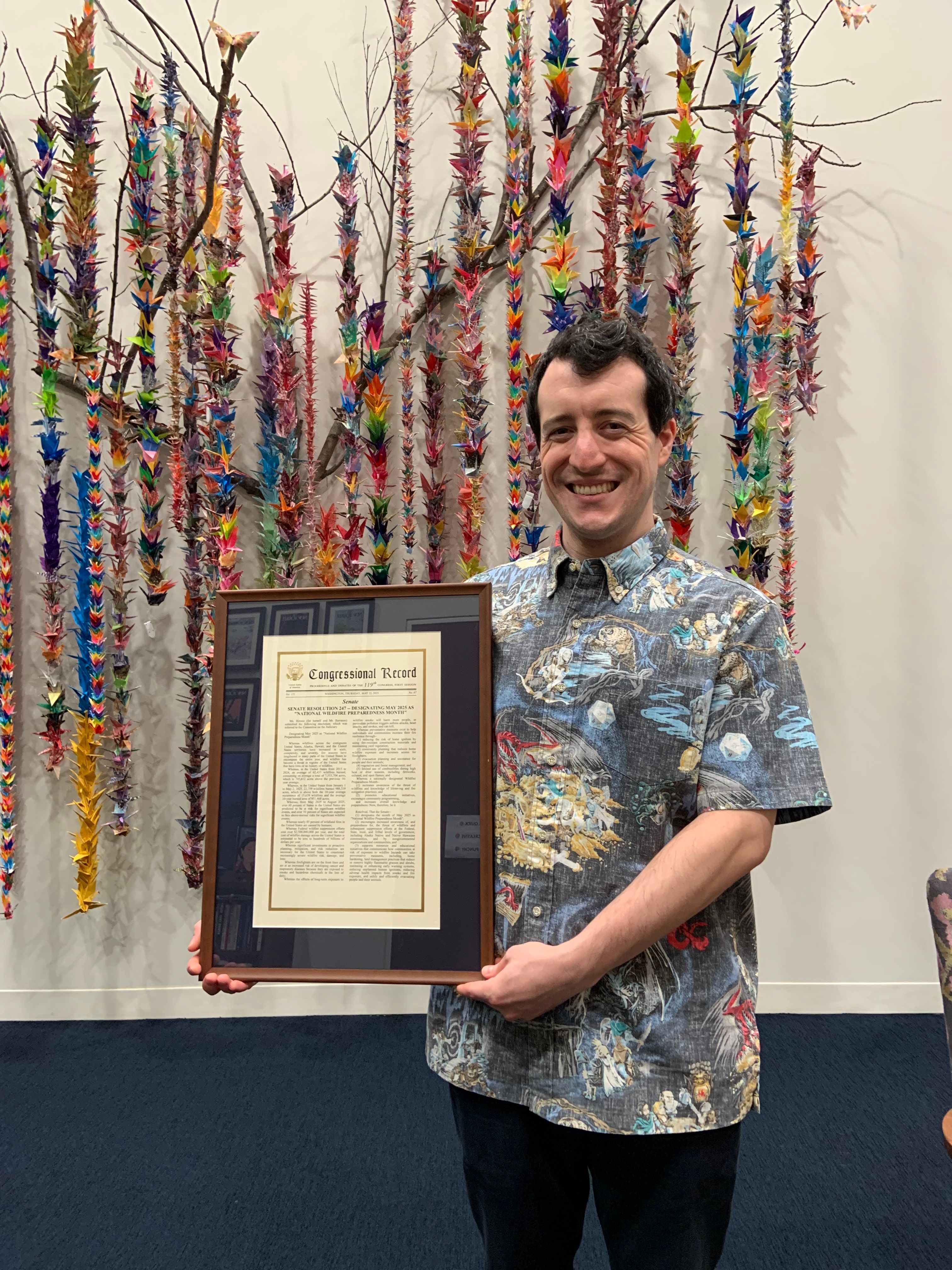 Robby holds a framed copy of S. Res. 247 inside Senator Hirono’s office.