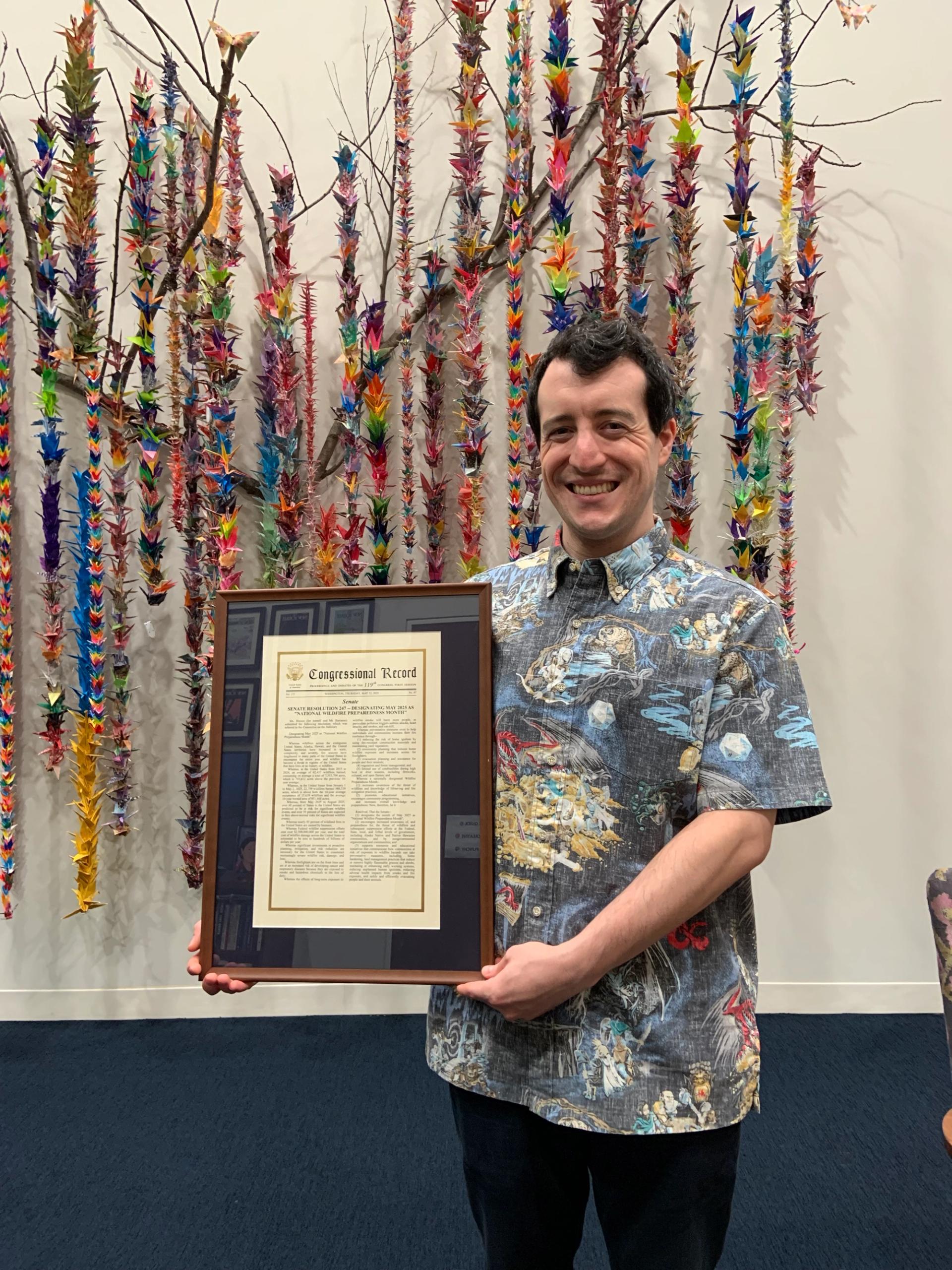 Robby holds a framed copy of S. Res. 247 inside Senator Hirono’s office.