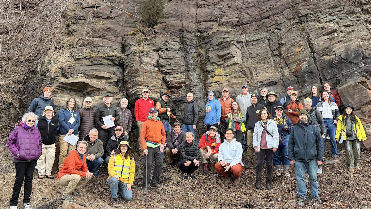Group photo of GSA Field Trip Participants posing in front of large rock outcrop in Connecticut