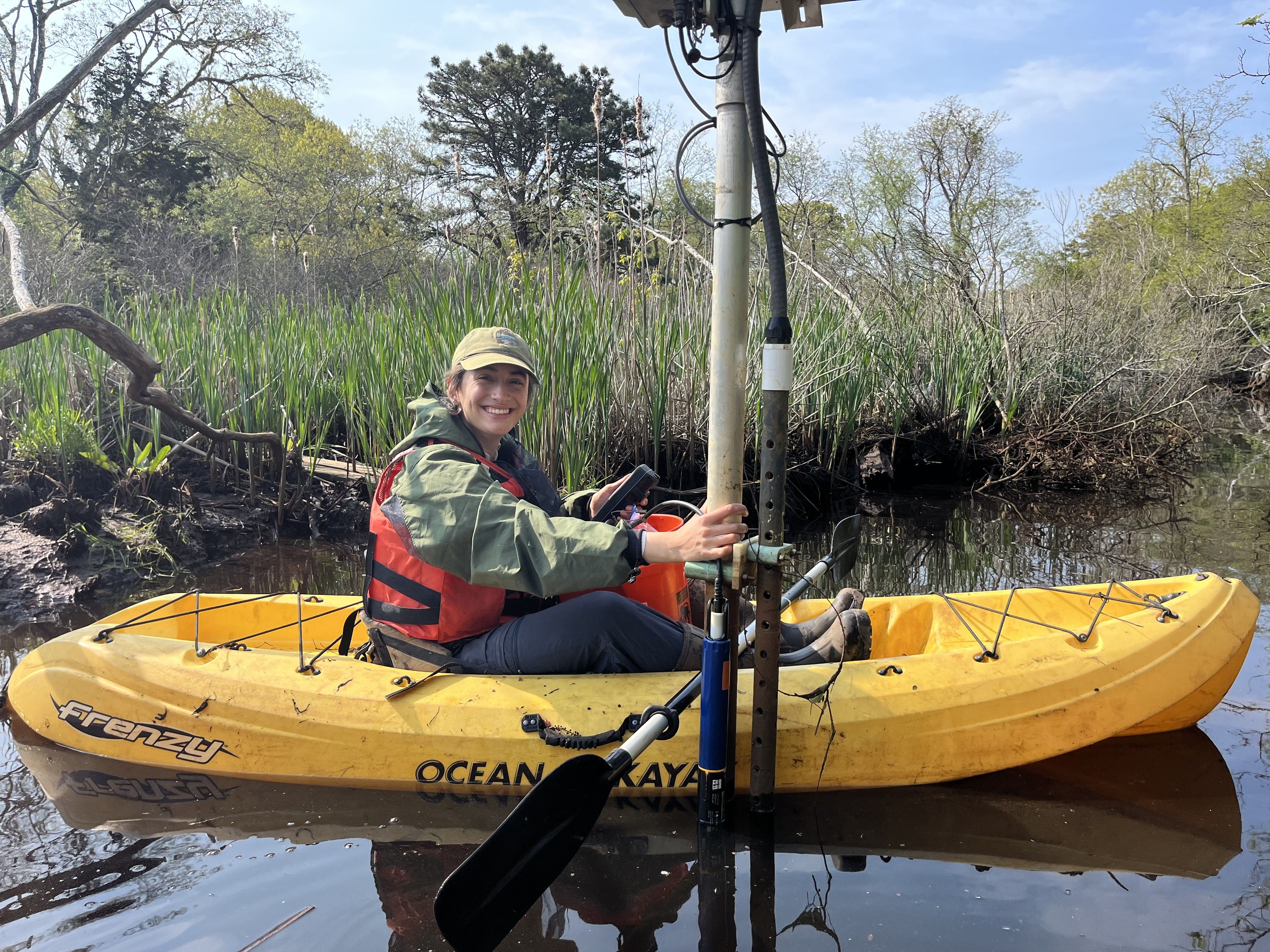 Photo of Scientists in the Parks Participant in a yellow boat on lake holding equipment for geological fieldwork