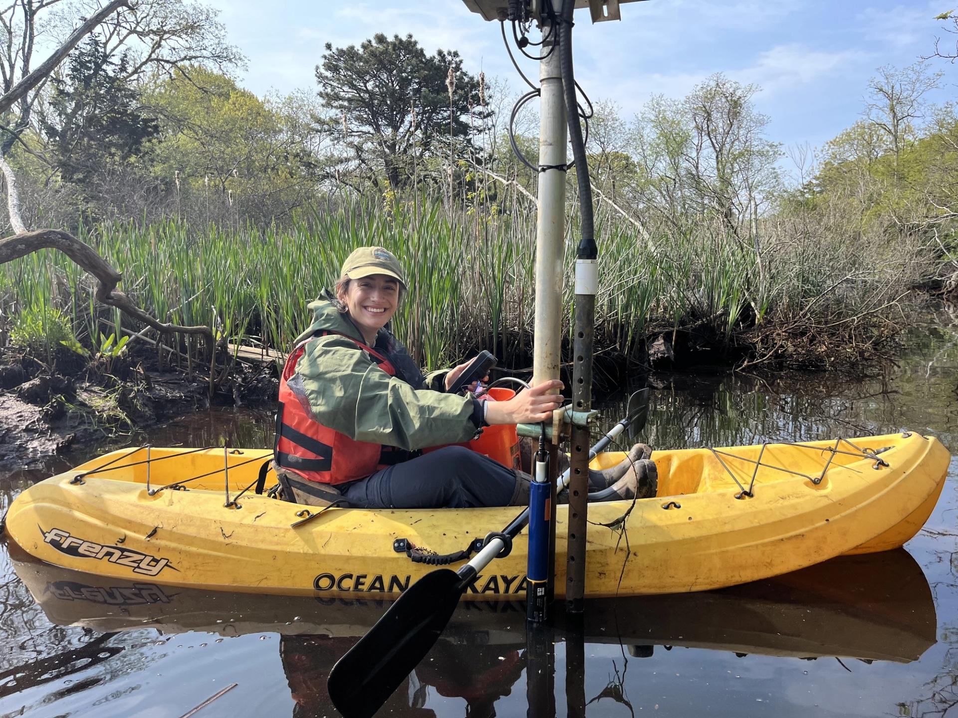 Photo of Scientists in the Parks Participant in a yellow boat on lake holding equipment for geological fieldwork
