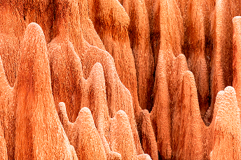 Close-up of vibrant orange and red rock formations with smooth, wavy surfaces, resembling cascading waves, conveying a sense of natural beauty and wonder.