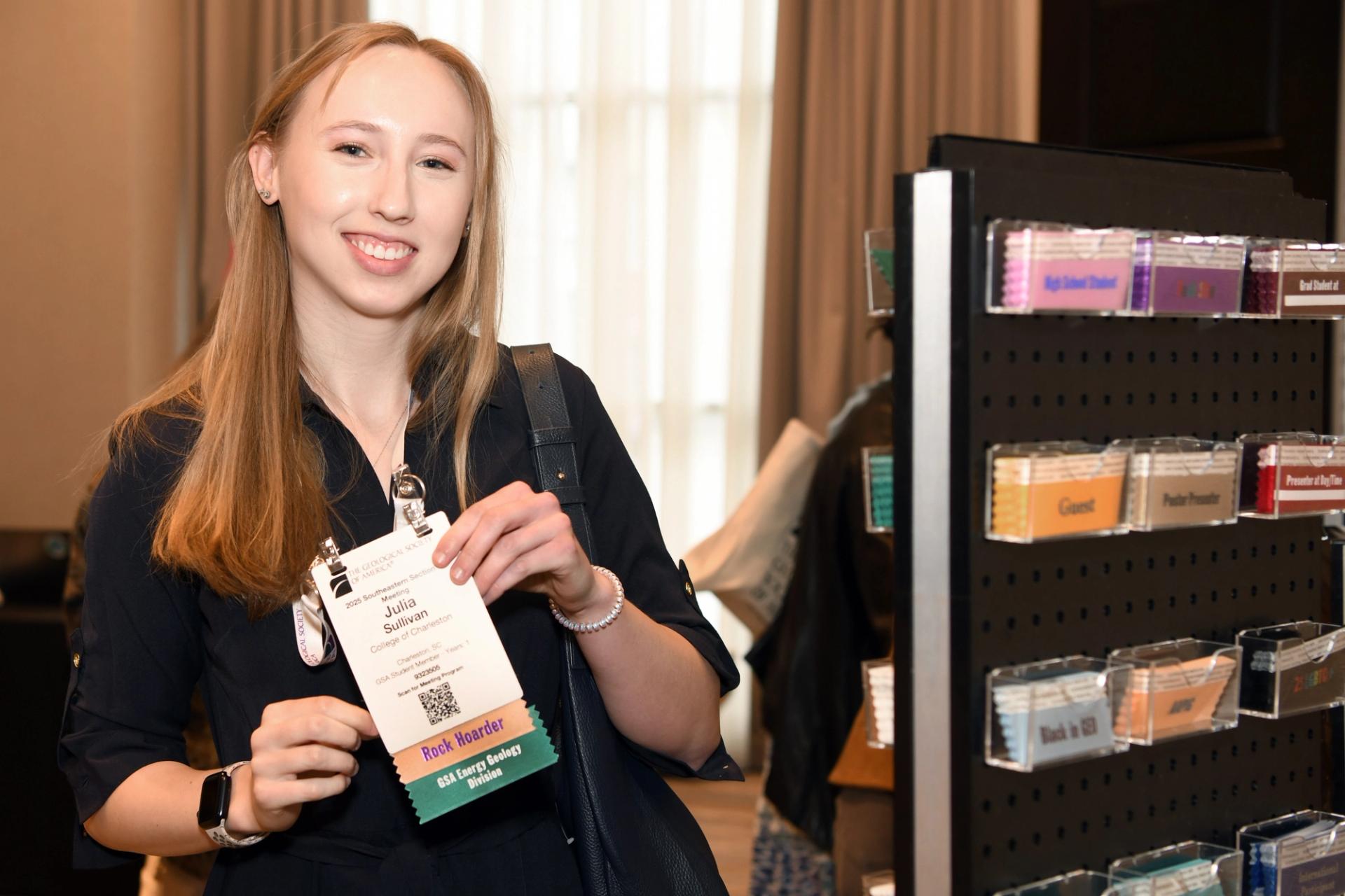 GSA meeting attendee smiling for photo in conference center near ribbon station at registration