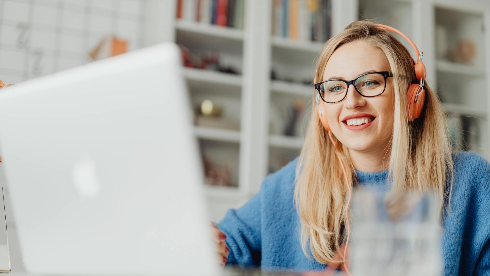 Image of young woman smiling while watching virtual webinar on laptop