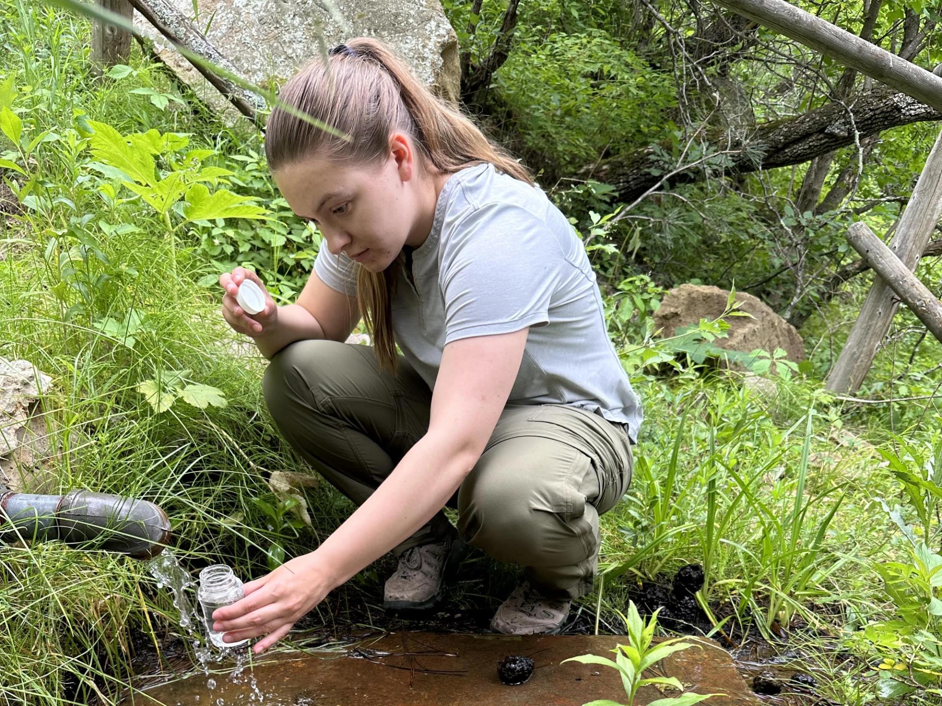 Photo of GeoCorps Participant in the field taking a water sample