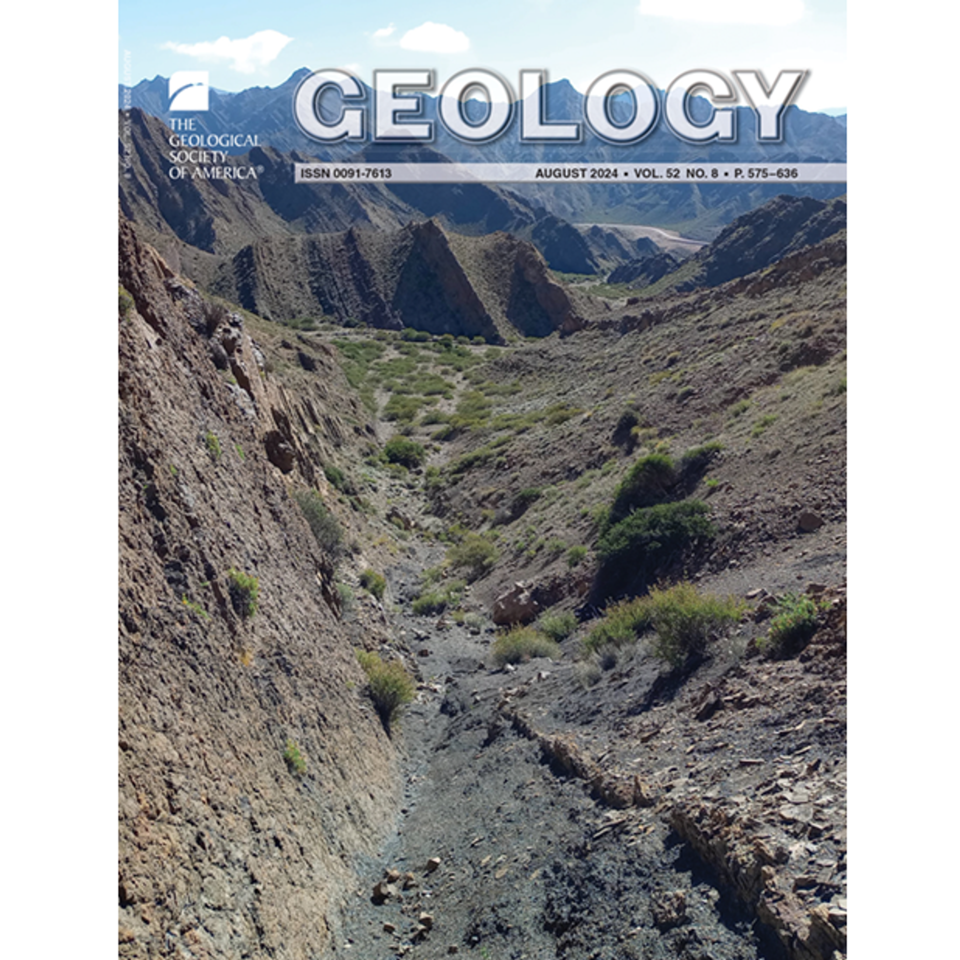 Rugged desert landscape with rocky terrain and sparse vegetation. Deep valleys and sharp mountain ridges stretch under a clear blue sky.