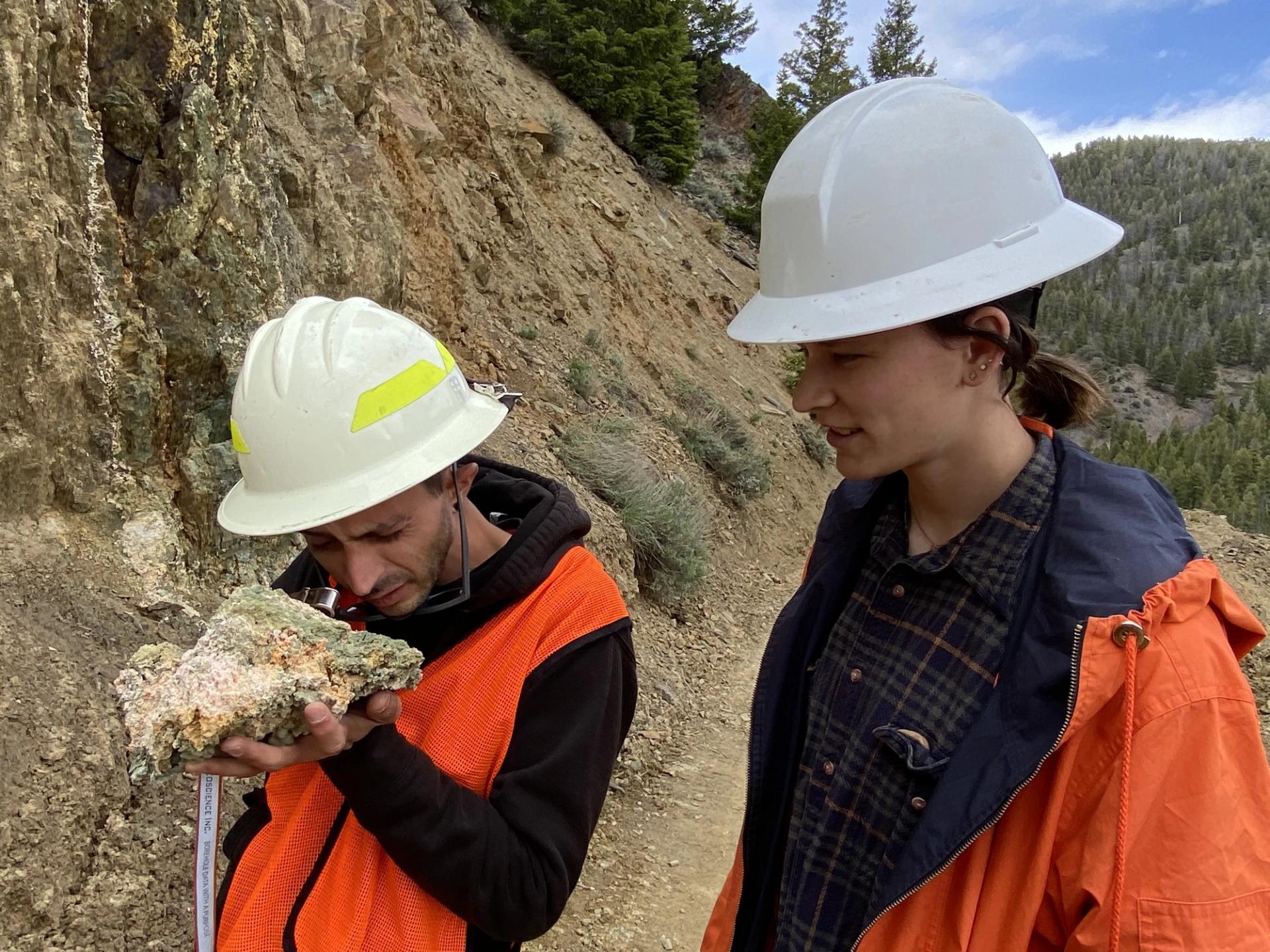 GeoCorps scientists wearing hard hats examining rocks in the field