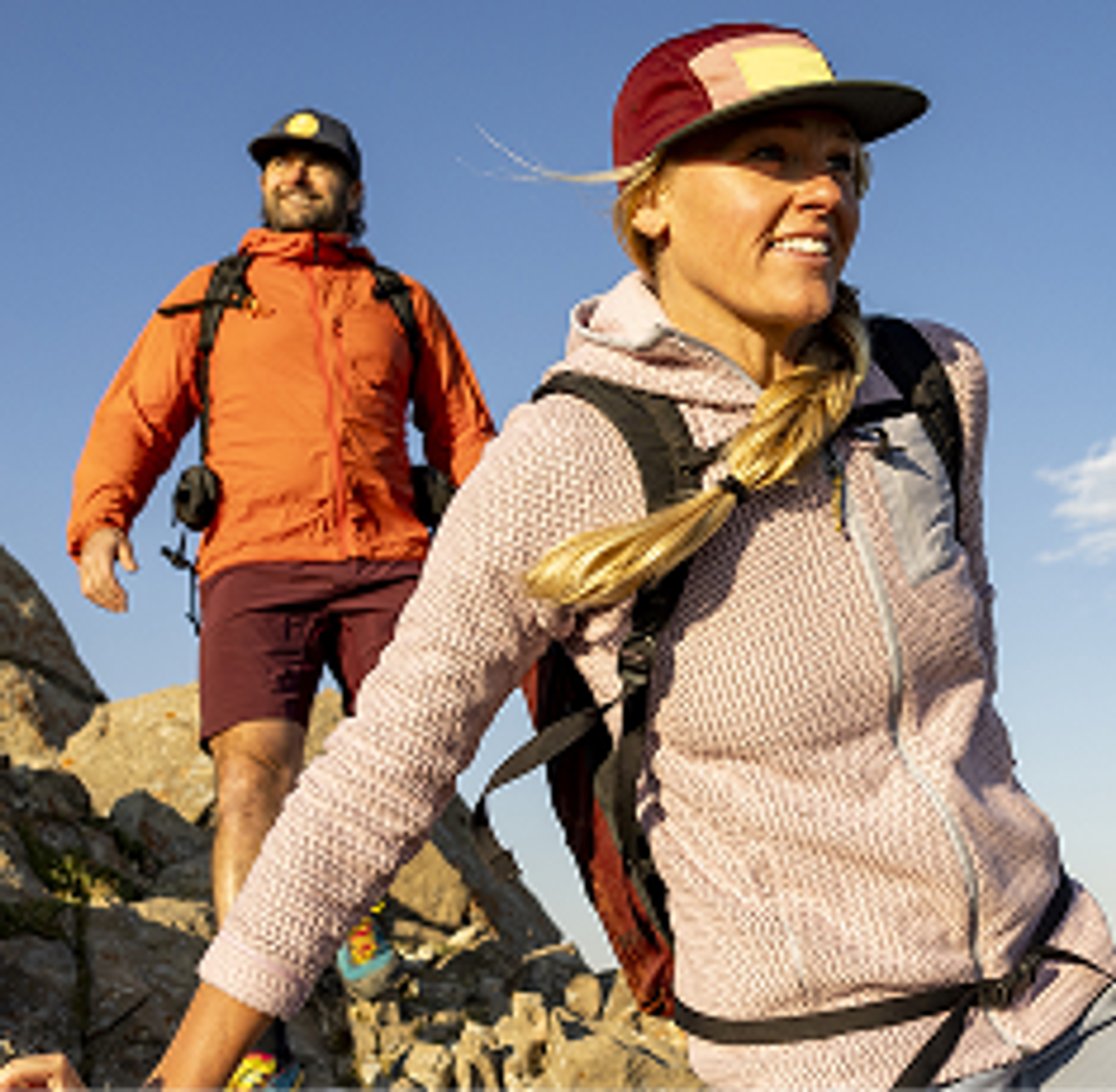 Two hikers walk over rocks.