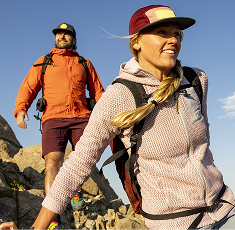 Two hikers walk over rocks.