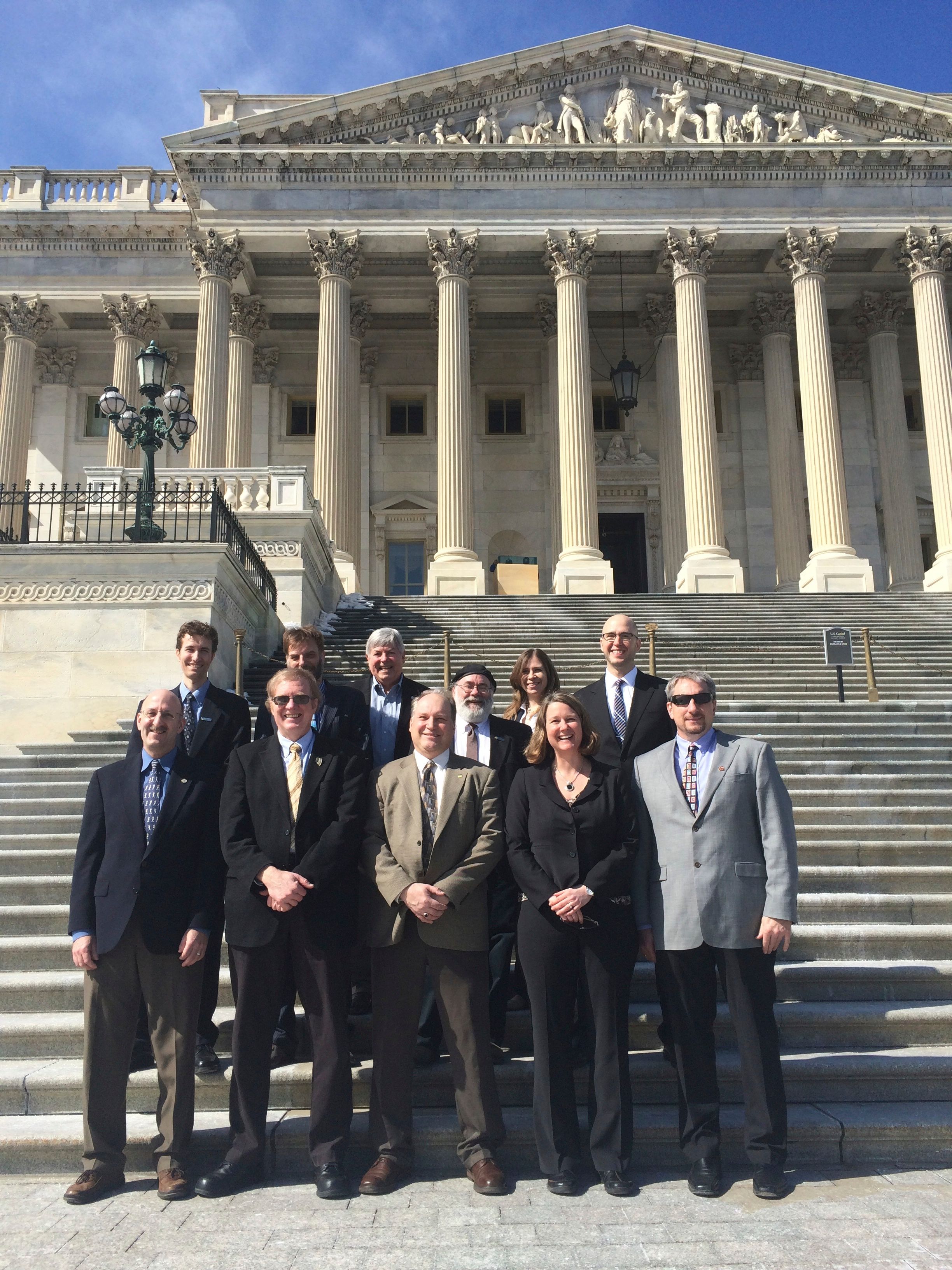 A group of people posing for a photo on the steps of the U.S. Capitol building