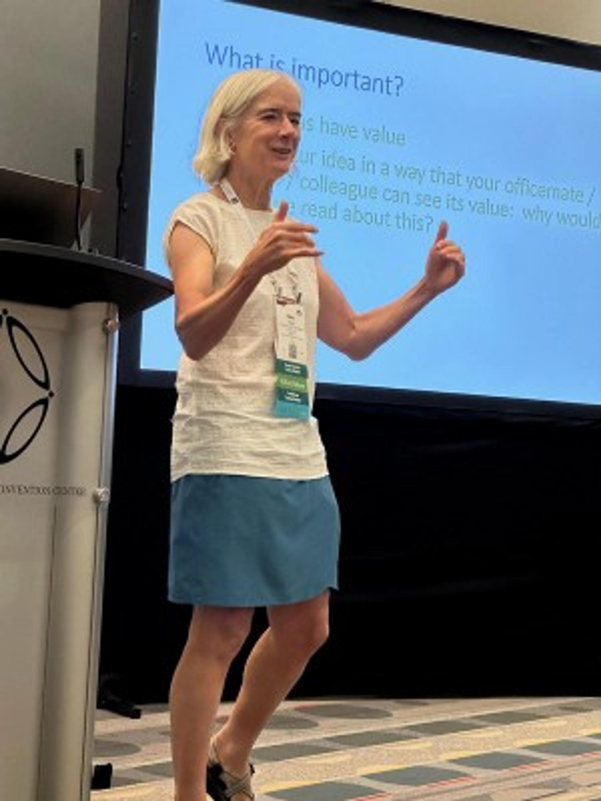 Image of presenter speaking in front of a podium and presentation