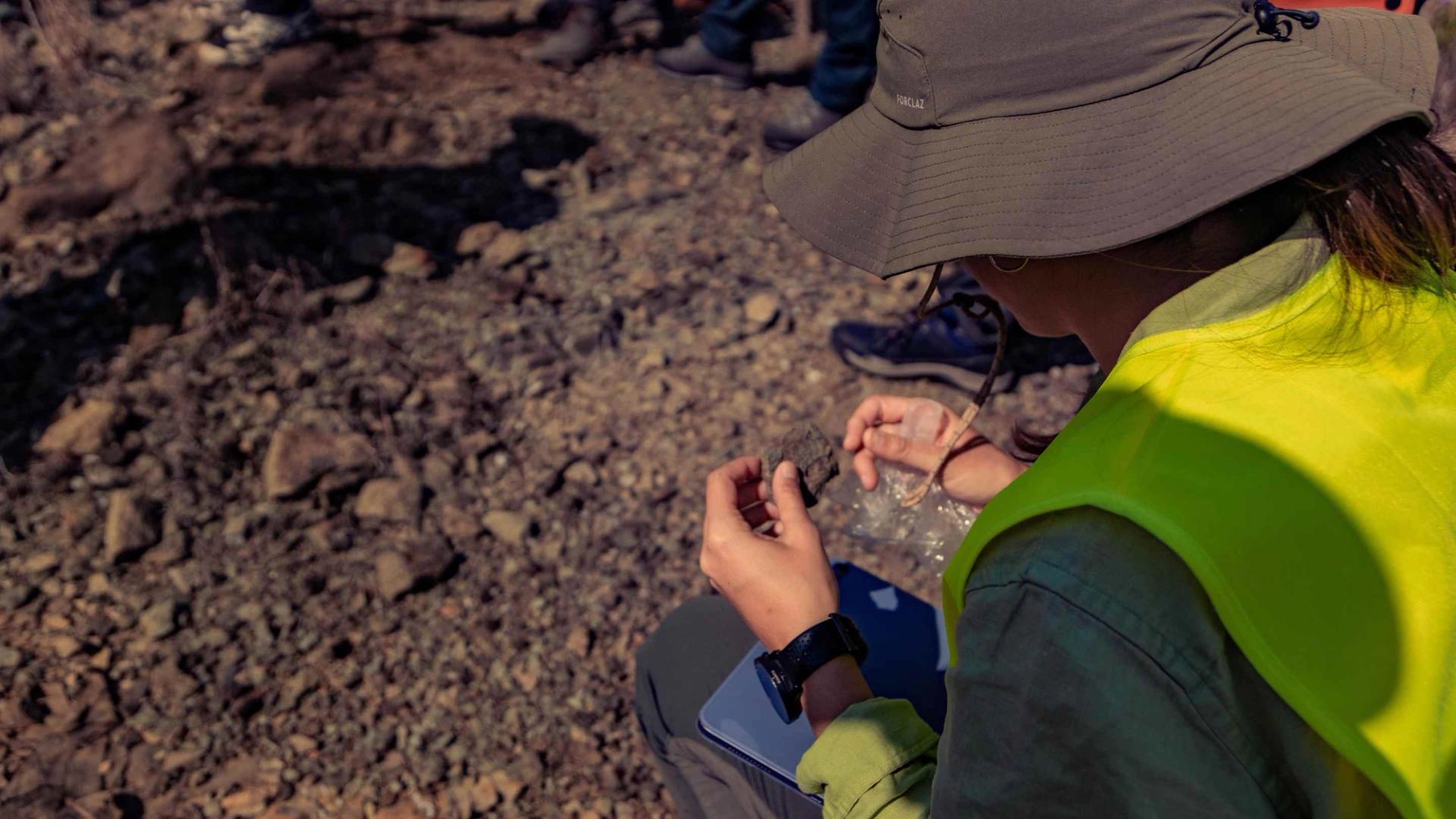 Field trip participant examining a rock close up
