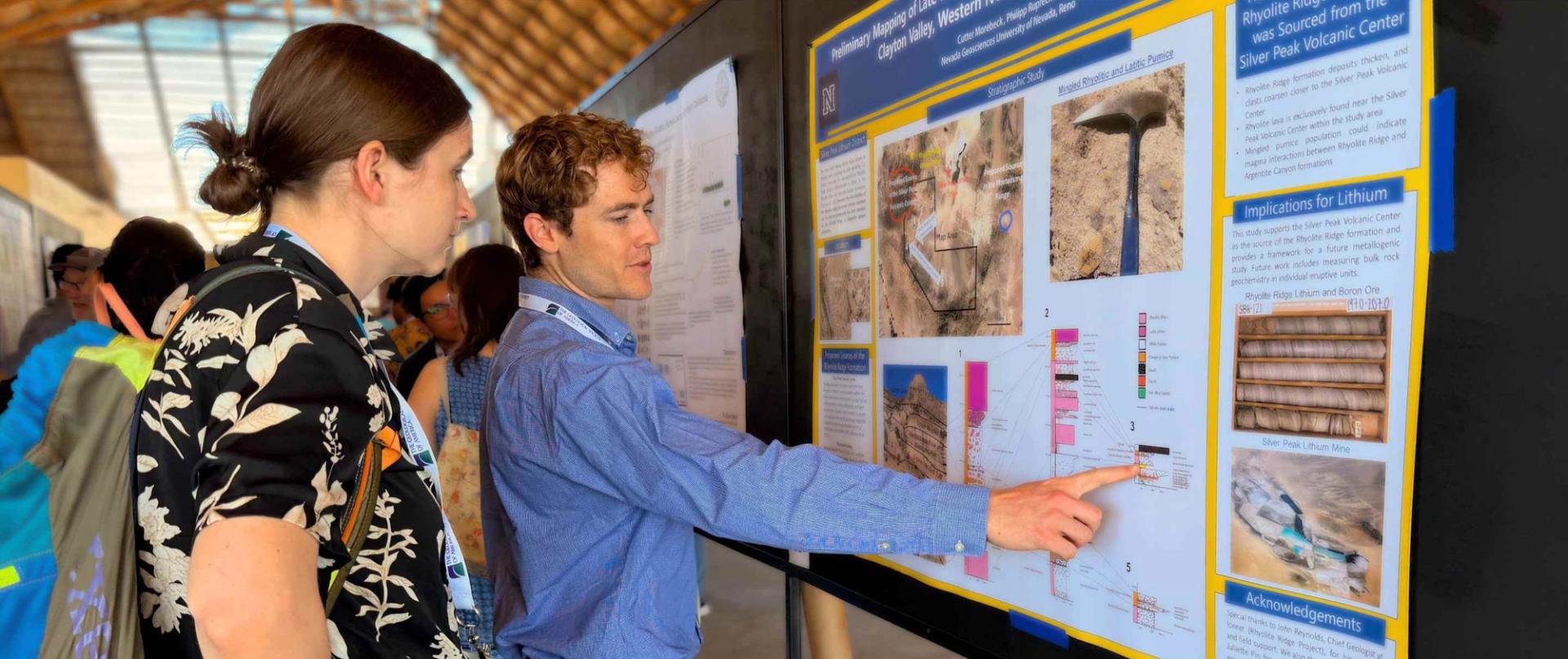 Landscape photo of poster presenter showing attendee his poster at GSA Meeting