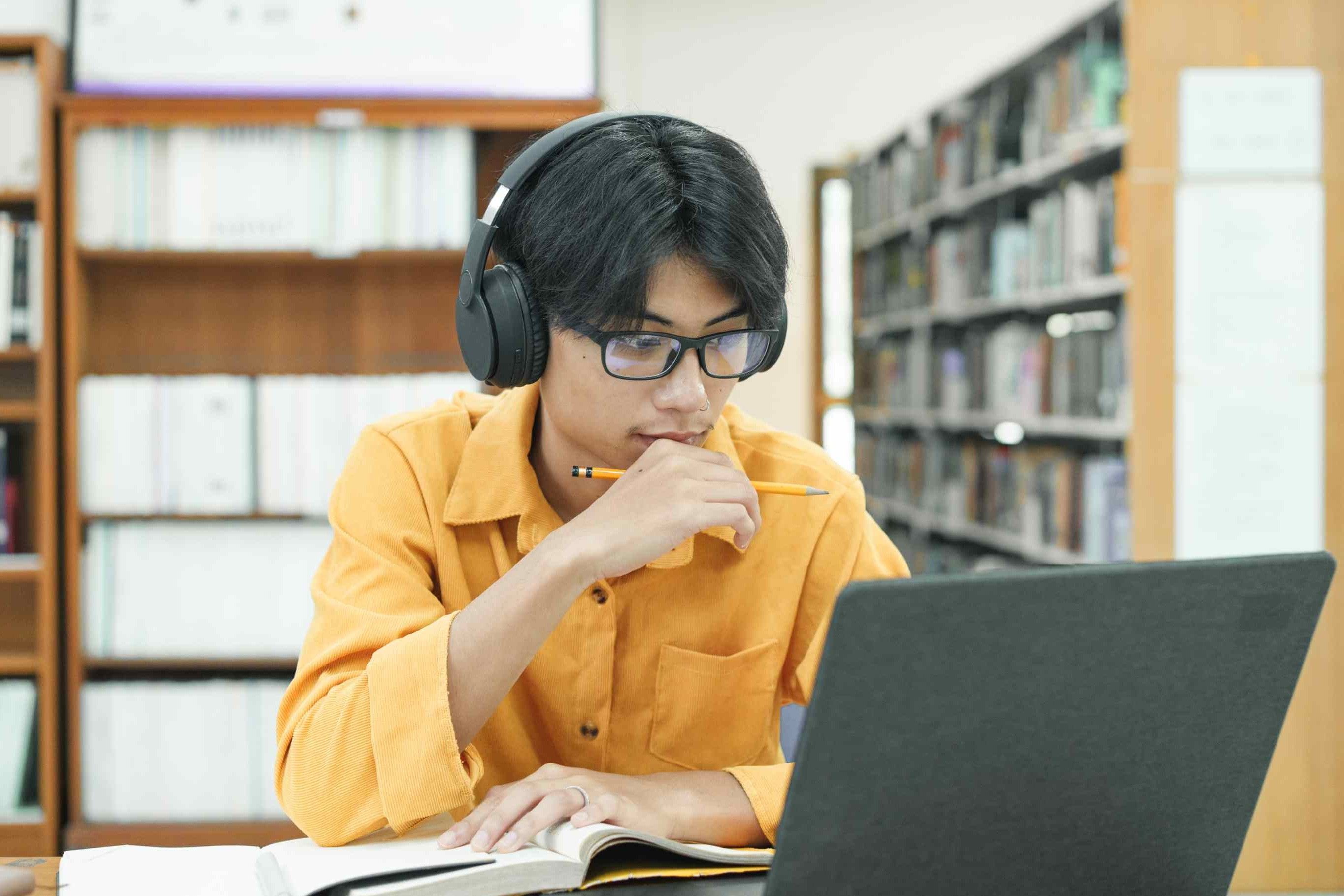 Image of young student studying on laptop in library