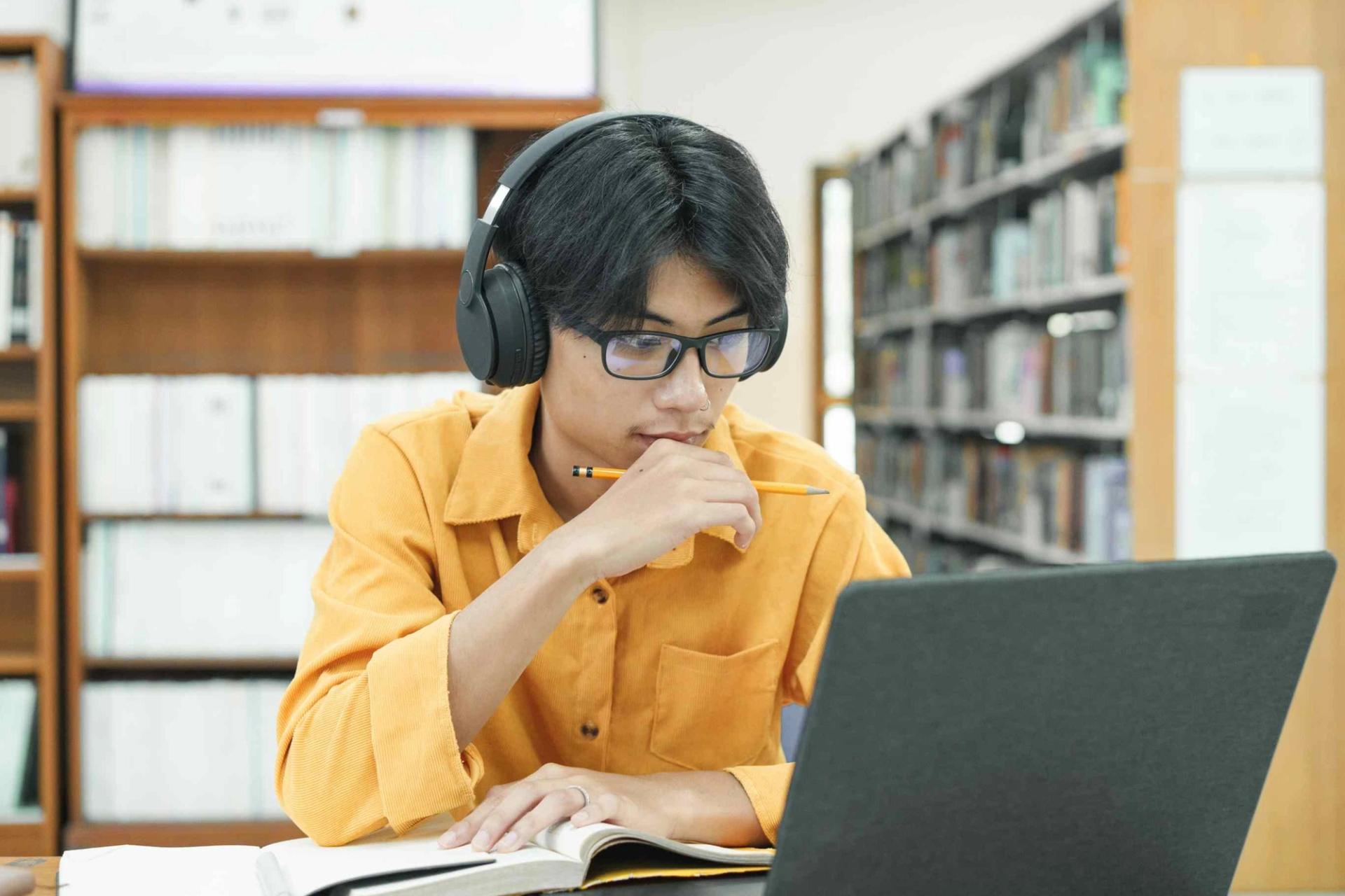 Image of young student studying on laptop in library