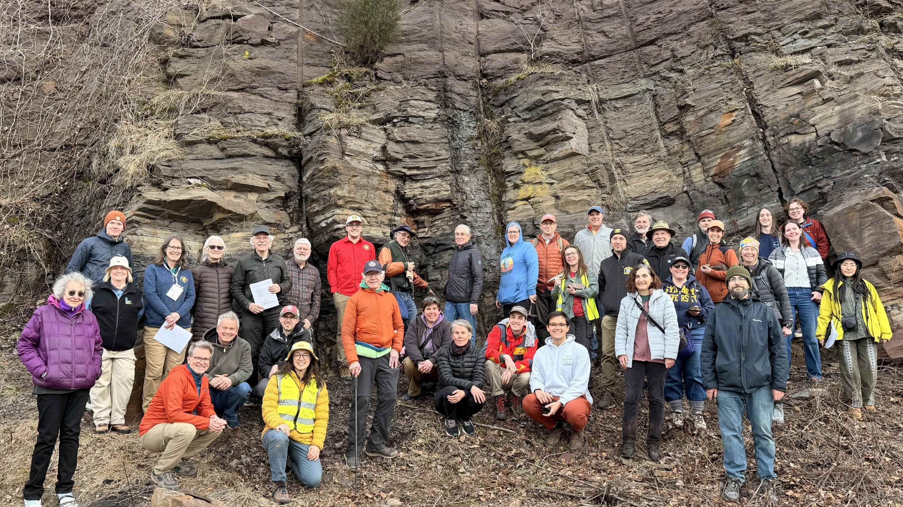 Group photo of field trip participants in front of large rock outcrop