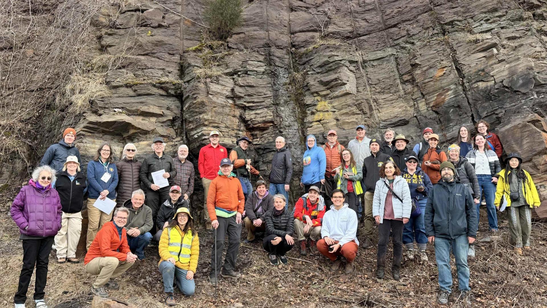 Group photo of field trip participants in front of large rock outcrop