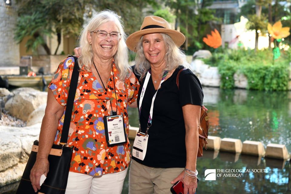 Two GSA Connects 2025 attendees pose together and smile as they stand in front of the San Antonio river near the Convention Center.