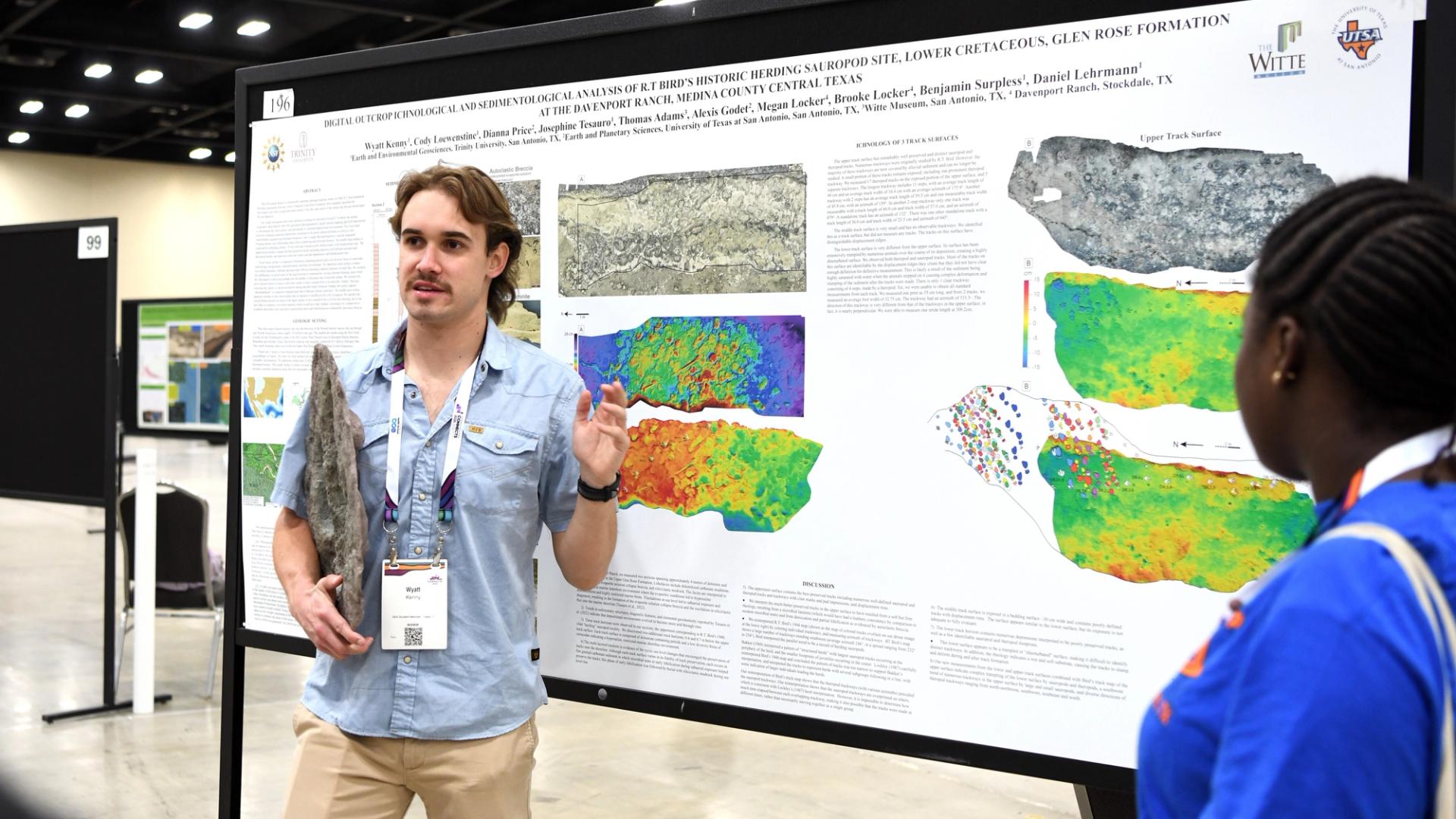 GSA meeting attendee presenting poster at annual Connects meeting while holding a large rock