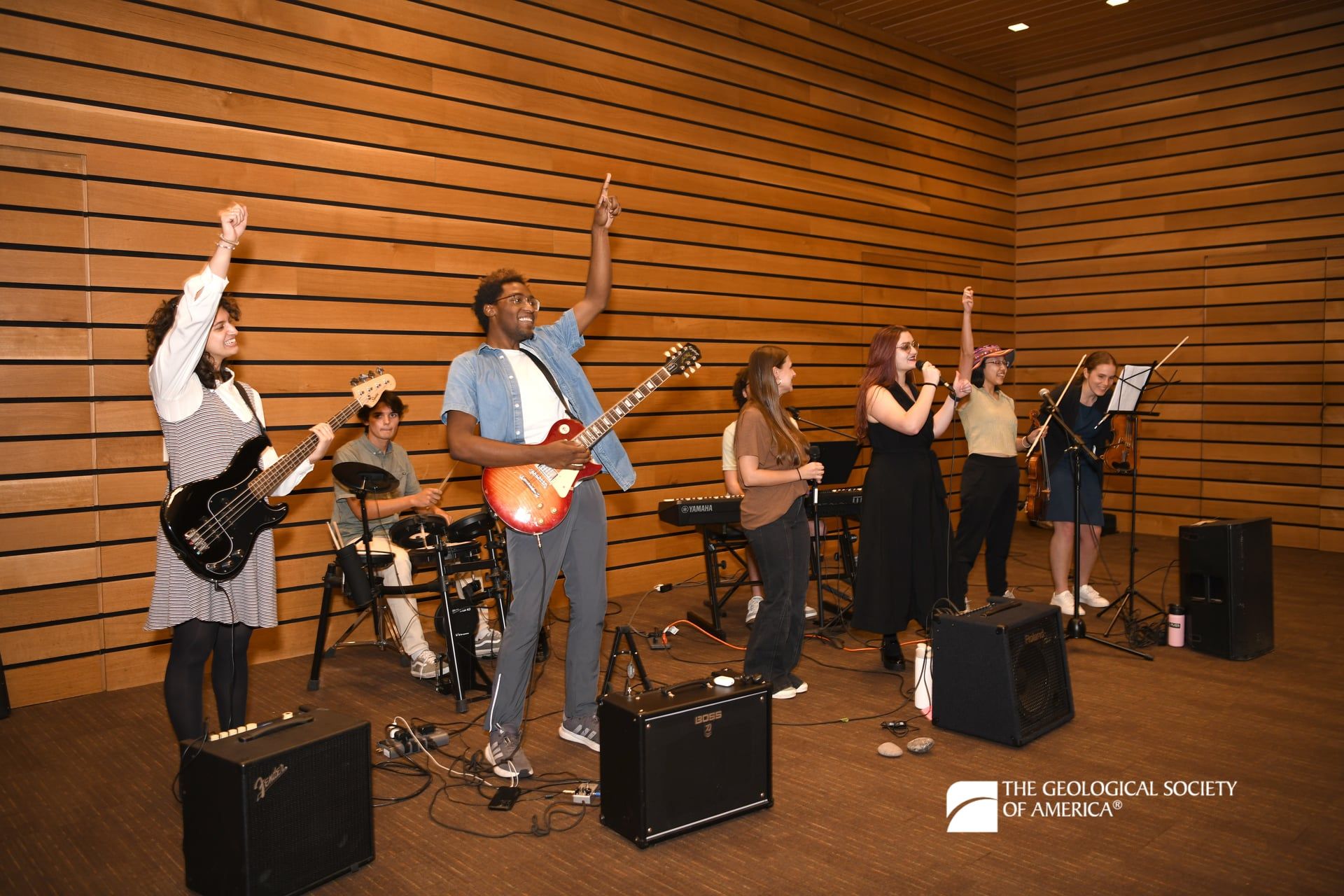 Several members of a band joyfully raise their arms as they perform at Connects 2025.