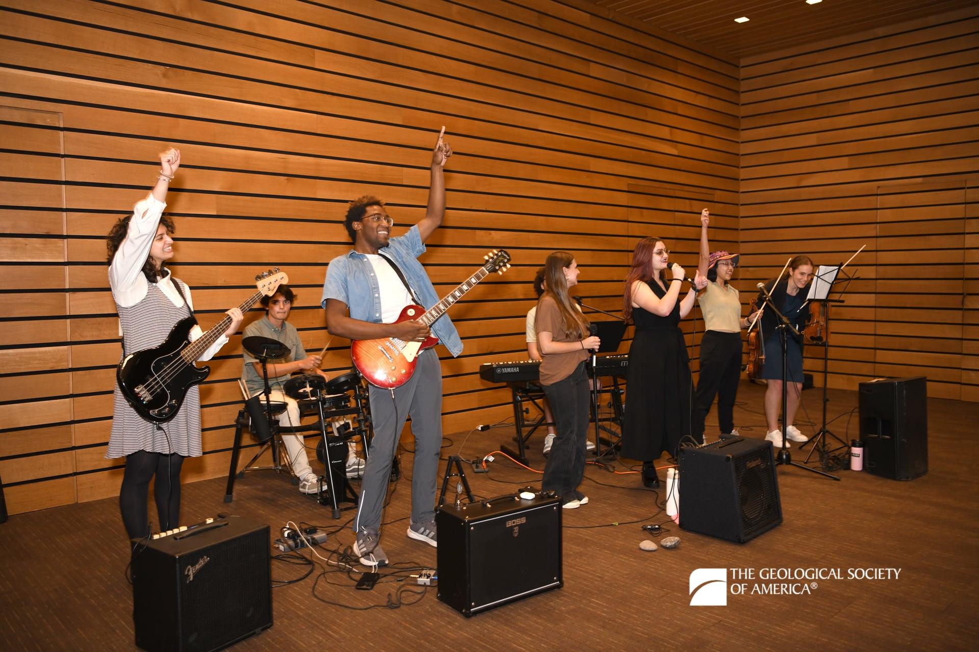Several members of a band joyfully raise their arms as they perform at Connects 2025.