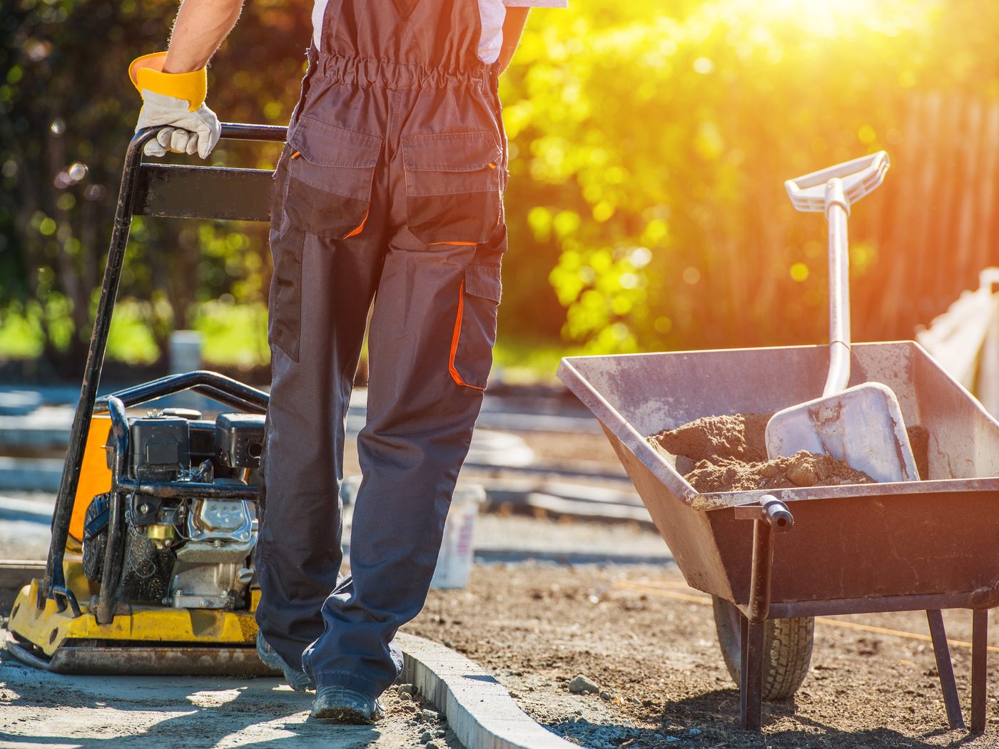 A tradesperson at work compacting a new path on a job site