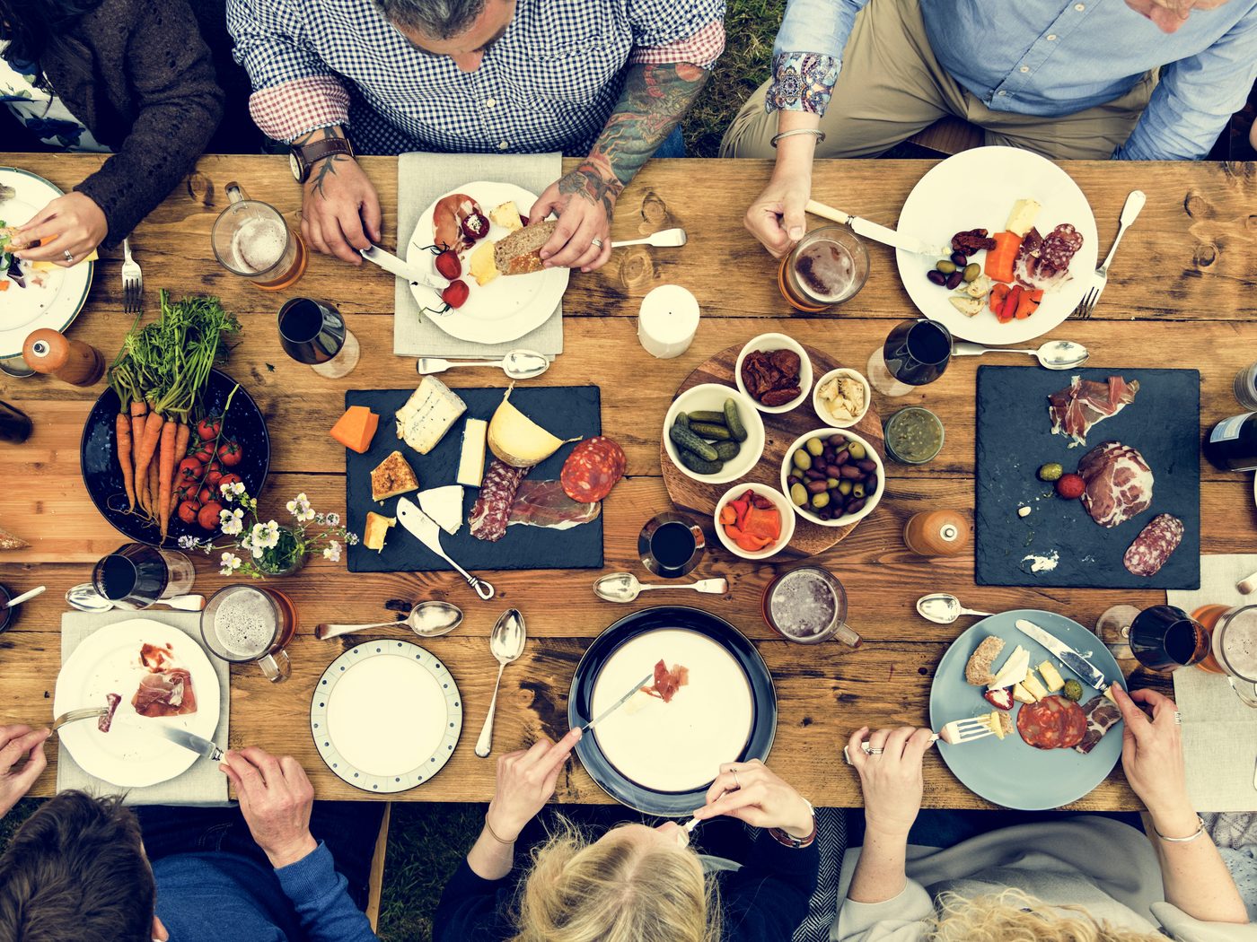 People gathered around a long table sharing a meal together outdoors