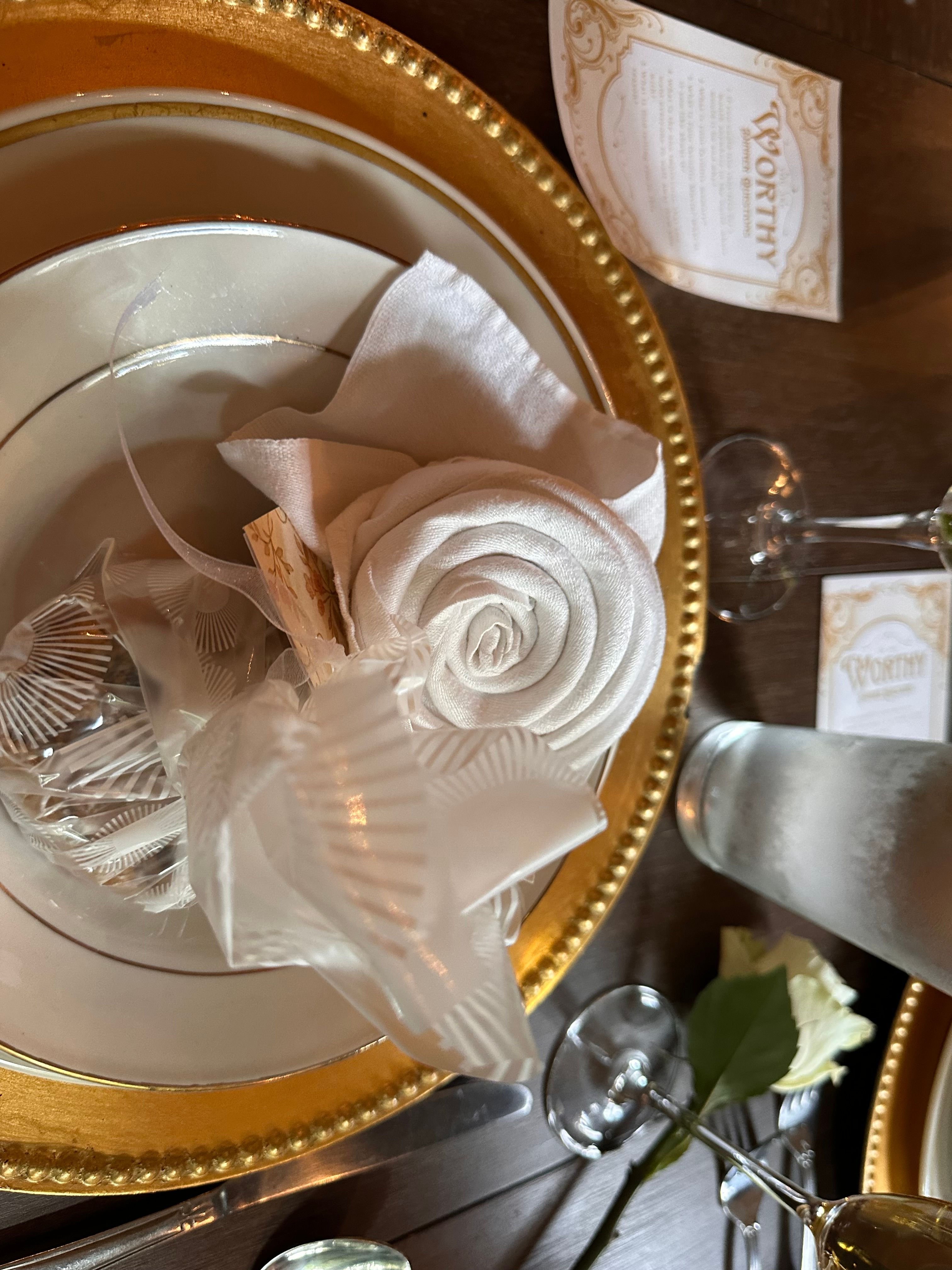 A place setting with a rose-folded napkin and a Worthy card