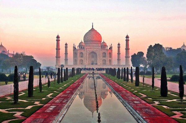 Sunrise hues of orange and pink color the domes of the Taj Mahal as the sun is rising on a cold morning.