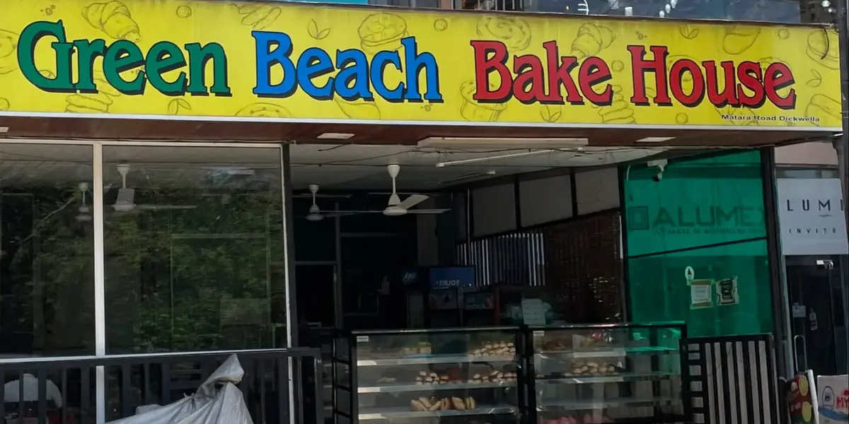 The yellow Green Beach Bake House sign and glass display counter on the main road in Dikwella, Sri Lanka