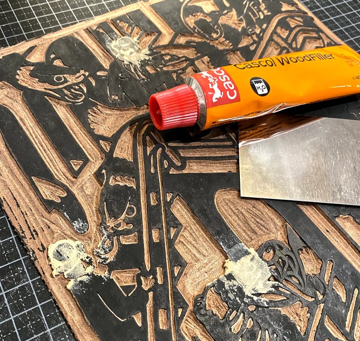 Using wood filler to patch a linocut.