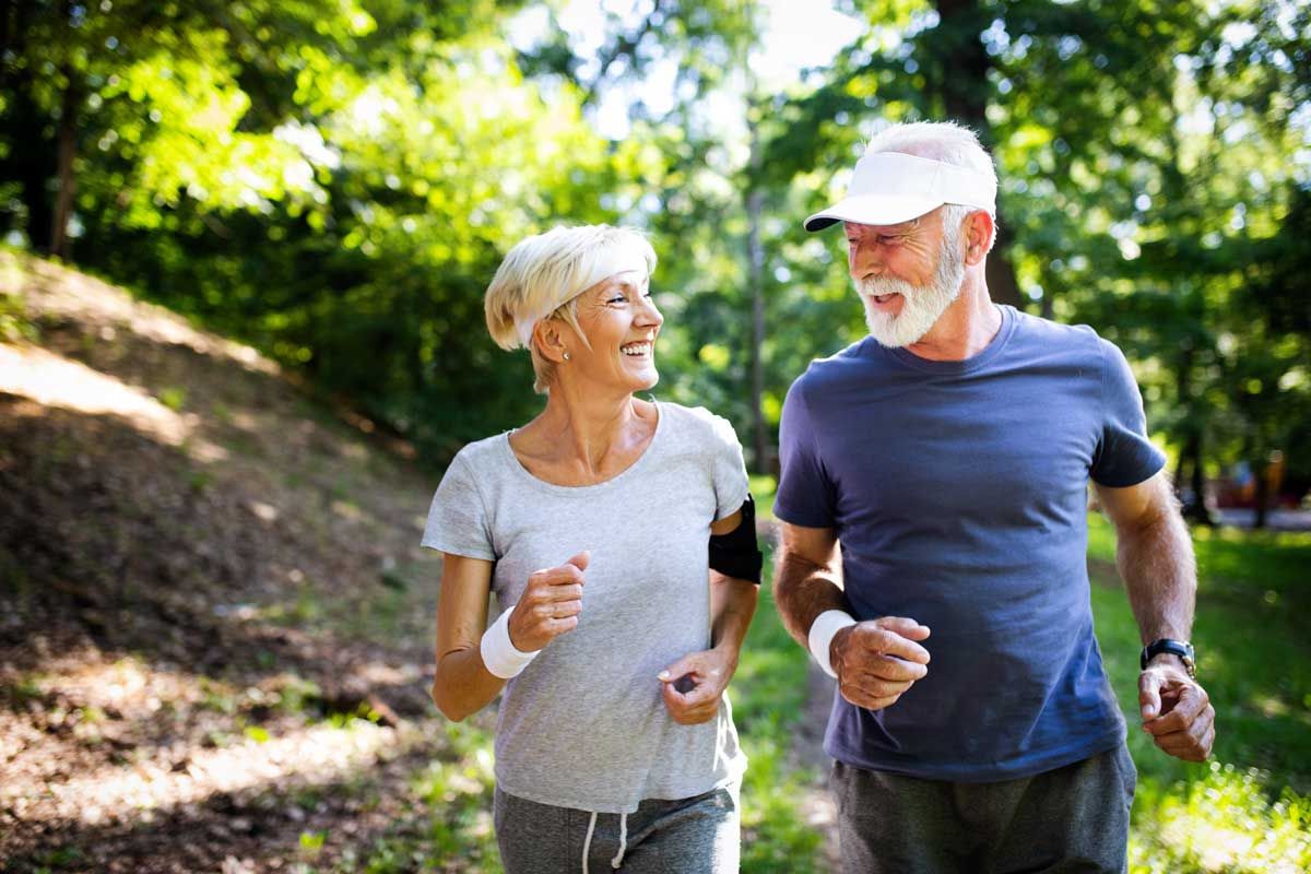 A woman in grey running with a man in blue. Both are looking at each other and smiling.