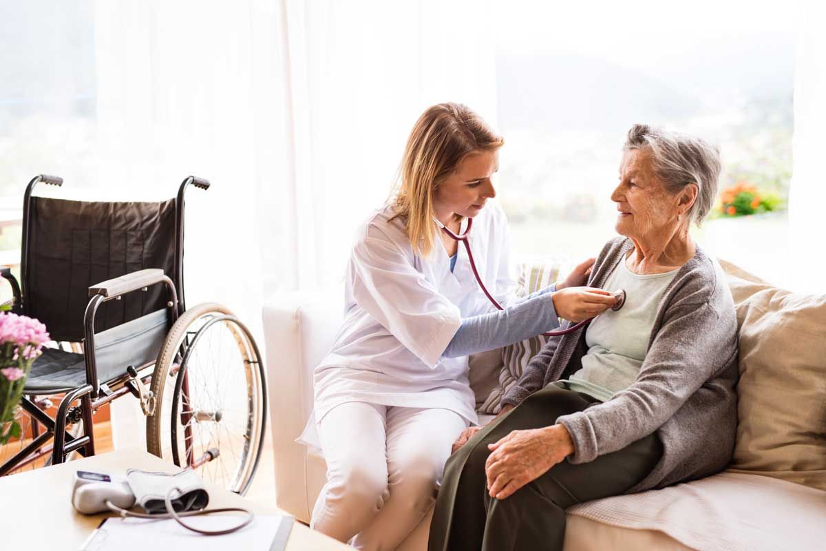 A woman doctor using a stethoscope on the chest of an older woman. 