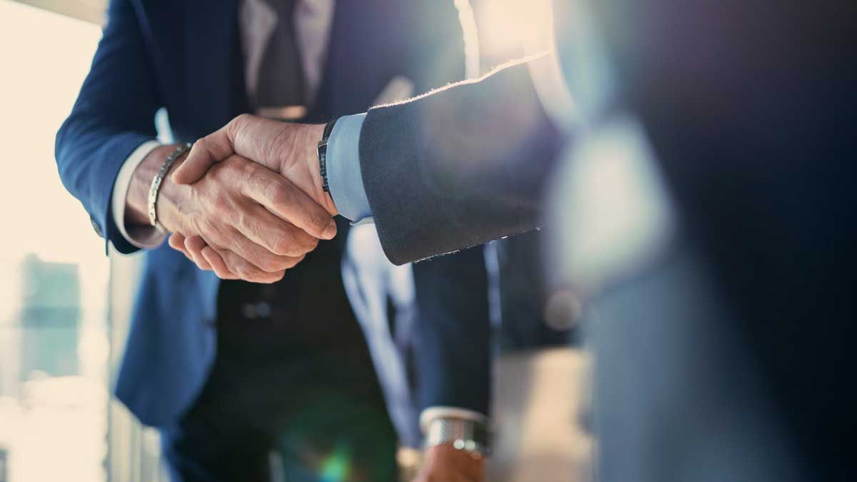 A close up of two men in suits shaking hands