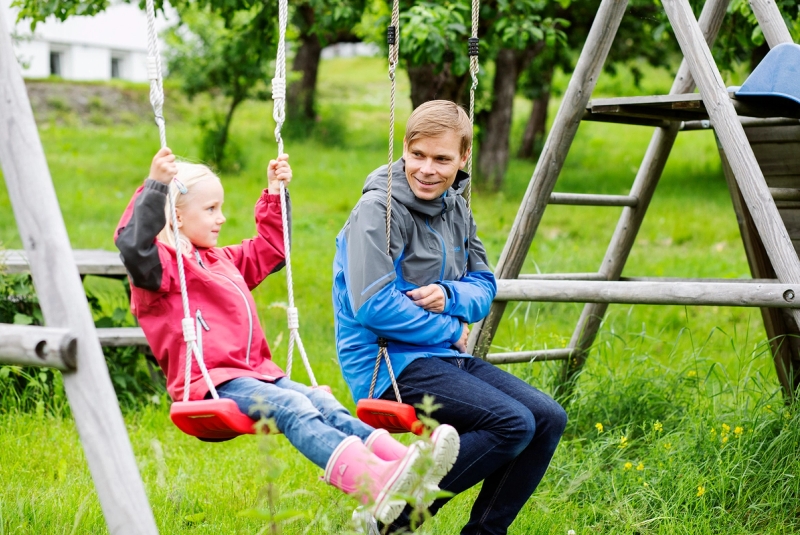 Familieven med barn på gynge