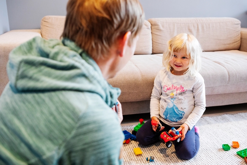 Familieven sidder på gulvet og leger