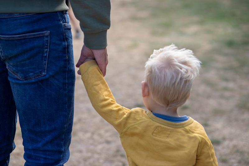 Dreng i Home-Start familie holder frivillig familieven i hånden