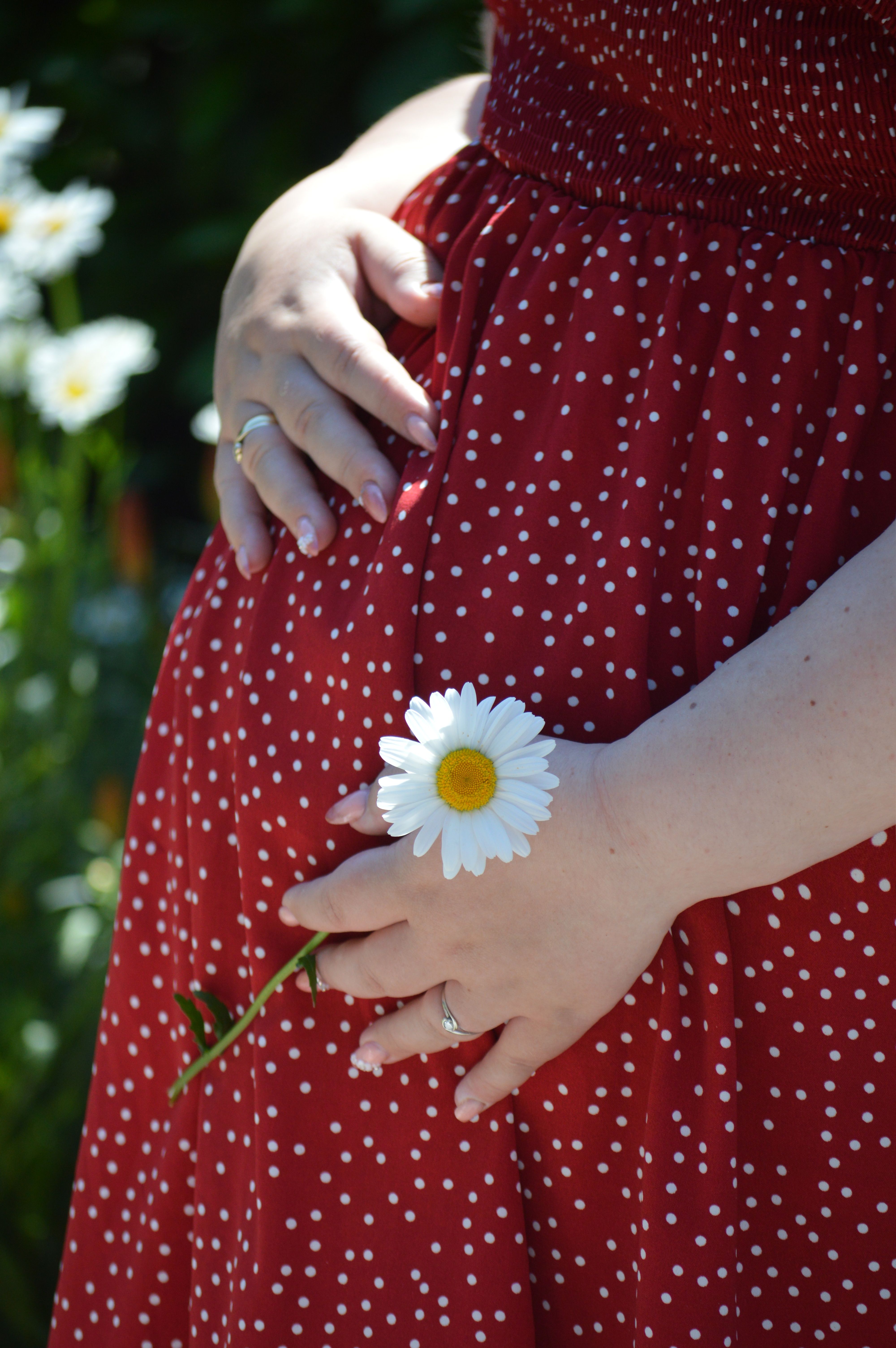 Gravid kvinde i rød kjole holder på maven