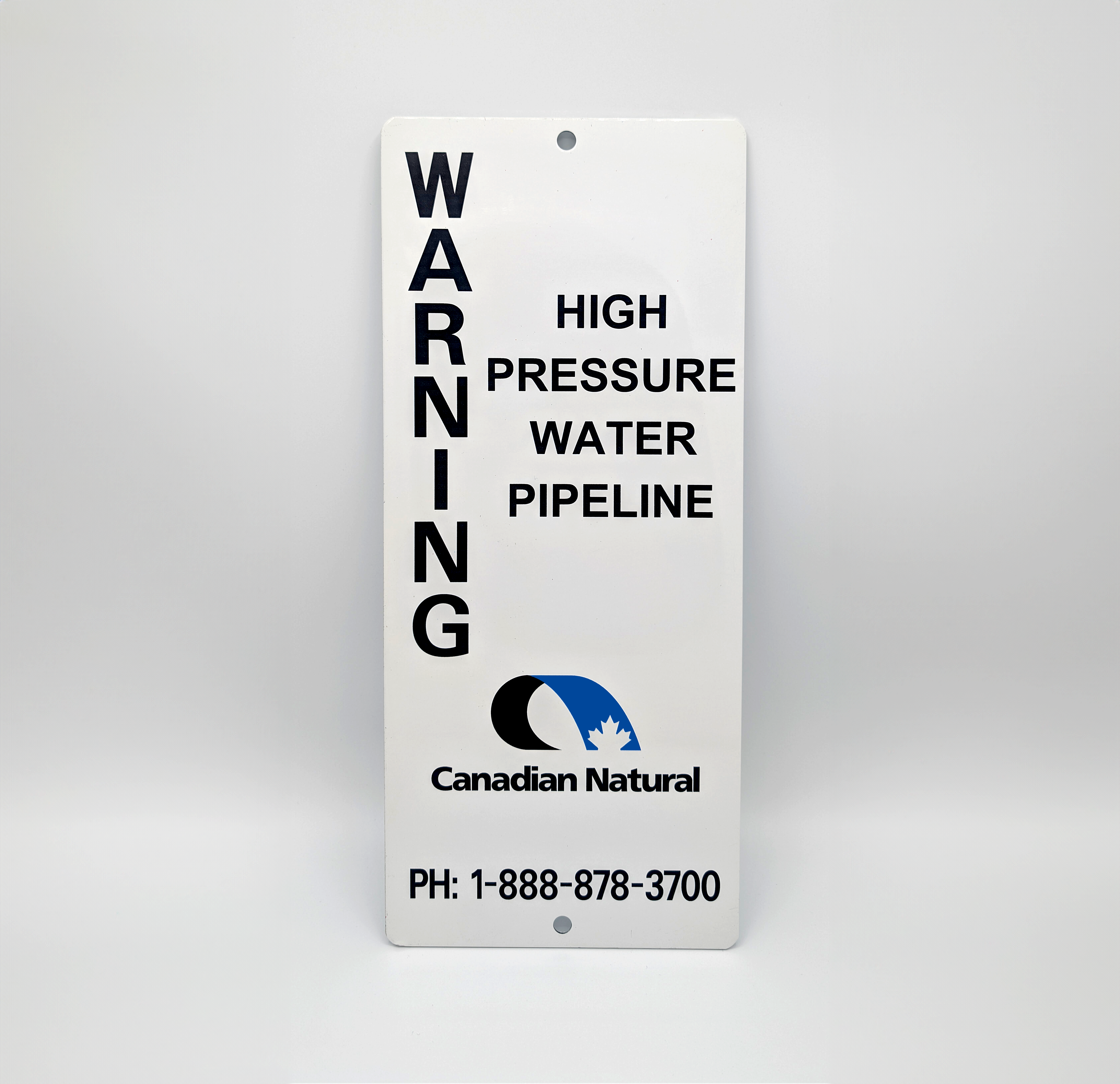 White aluminum warning sign reading ‘WARNING: High Pressure Water Pipeline’ with Canadian Natural logo and contact phone number.
