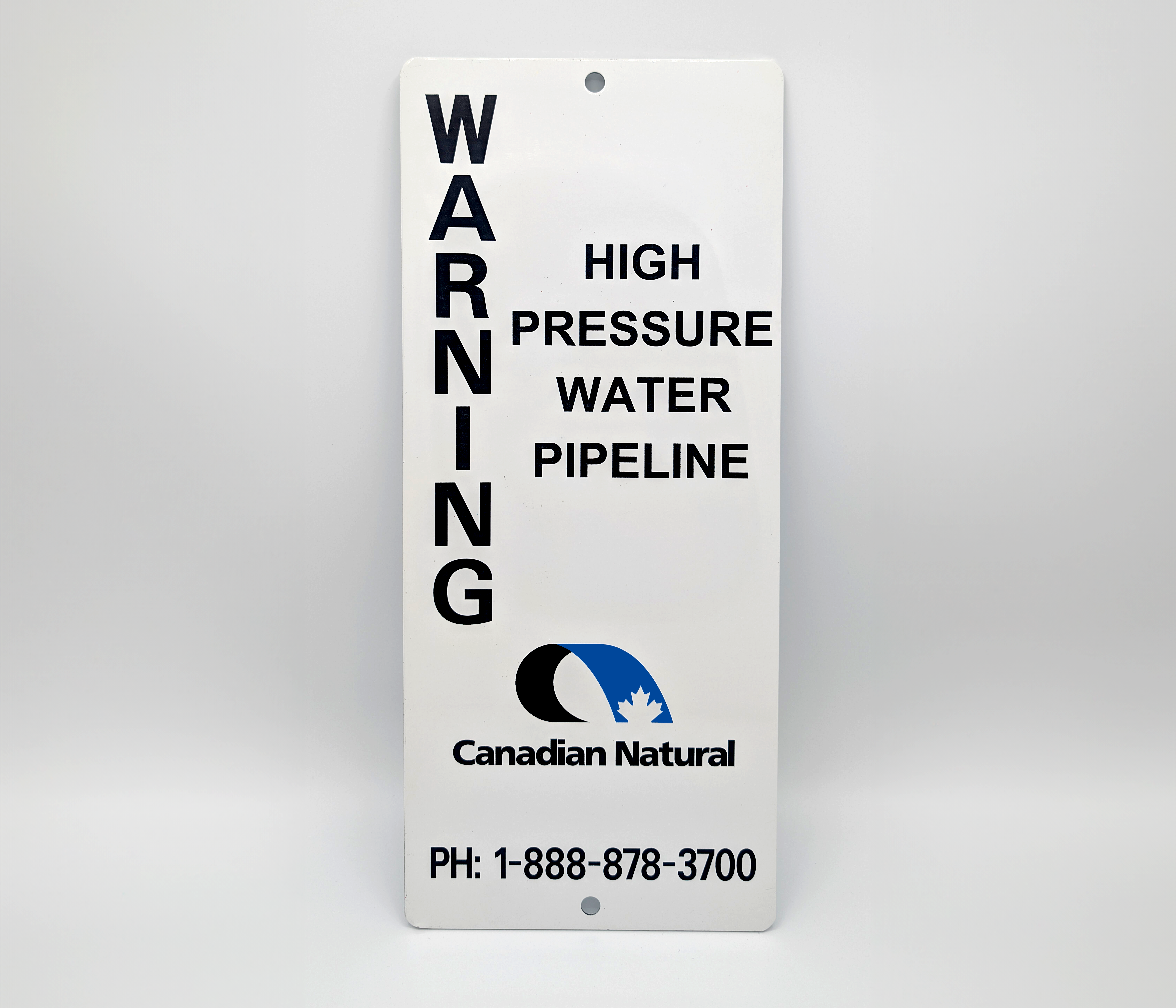 White aluminum warning sign reading ‘WARNING: High Pressure Water Pipeline’ with Canadian Natural logo and contact phone number.