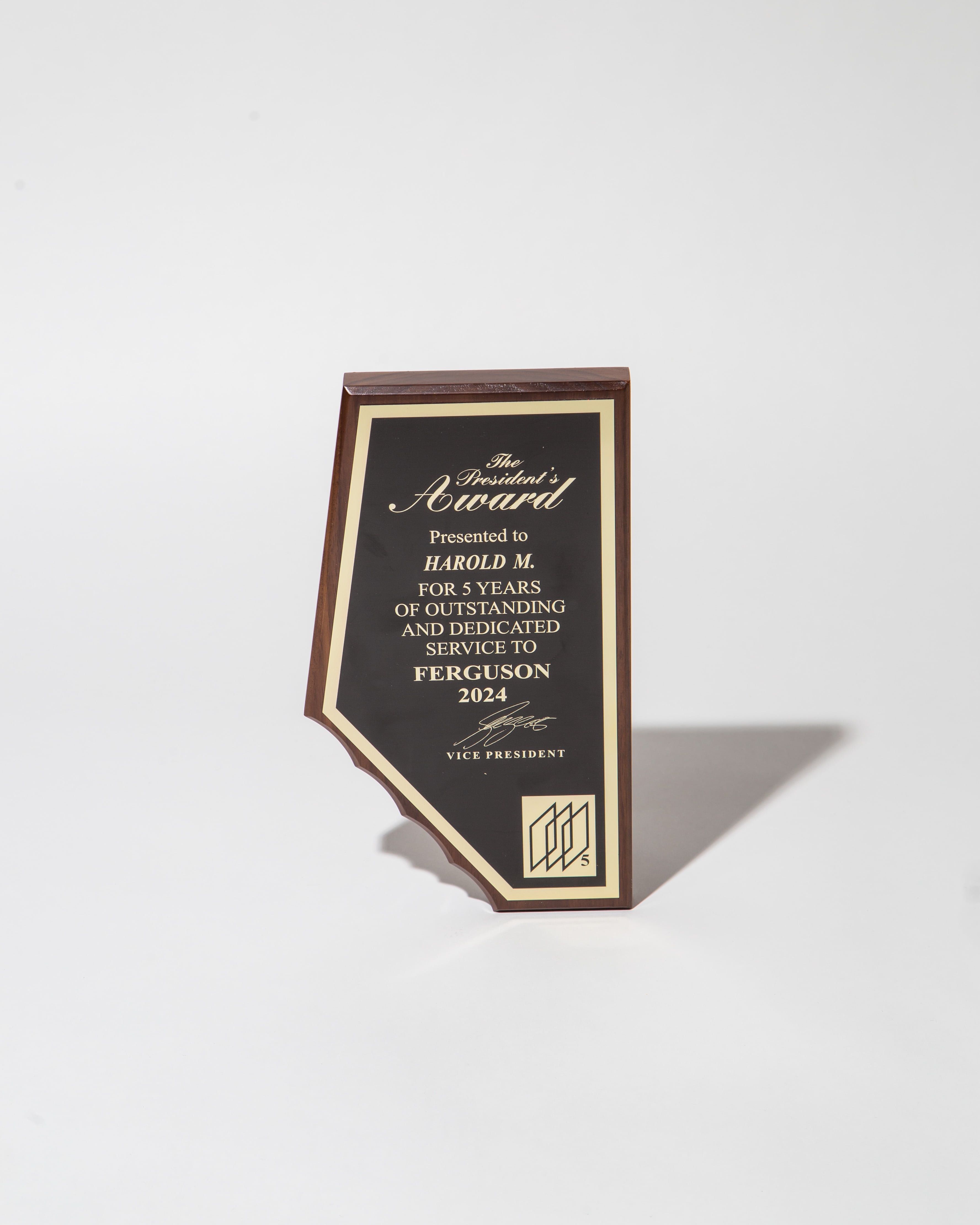 Wooden plaque with gold lettering for the President's Award, honoring 5 years of service in 2024.