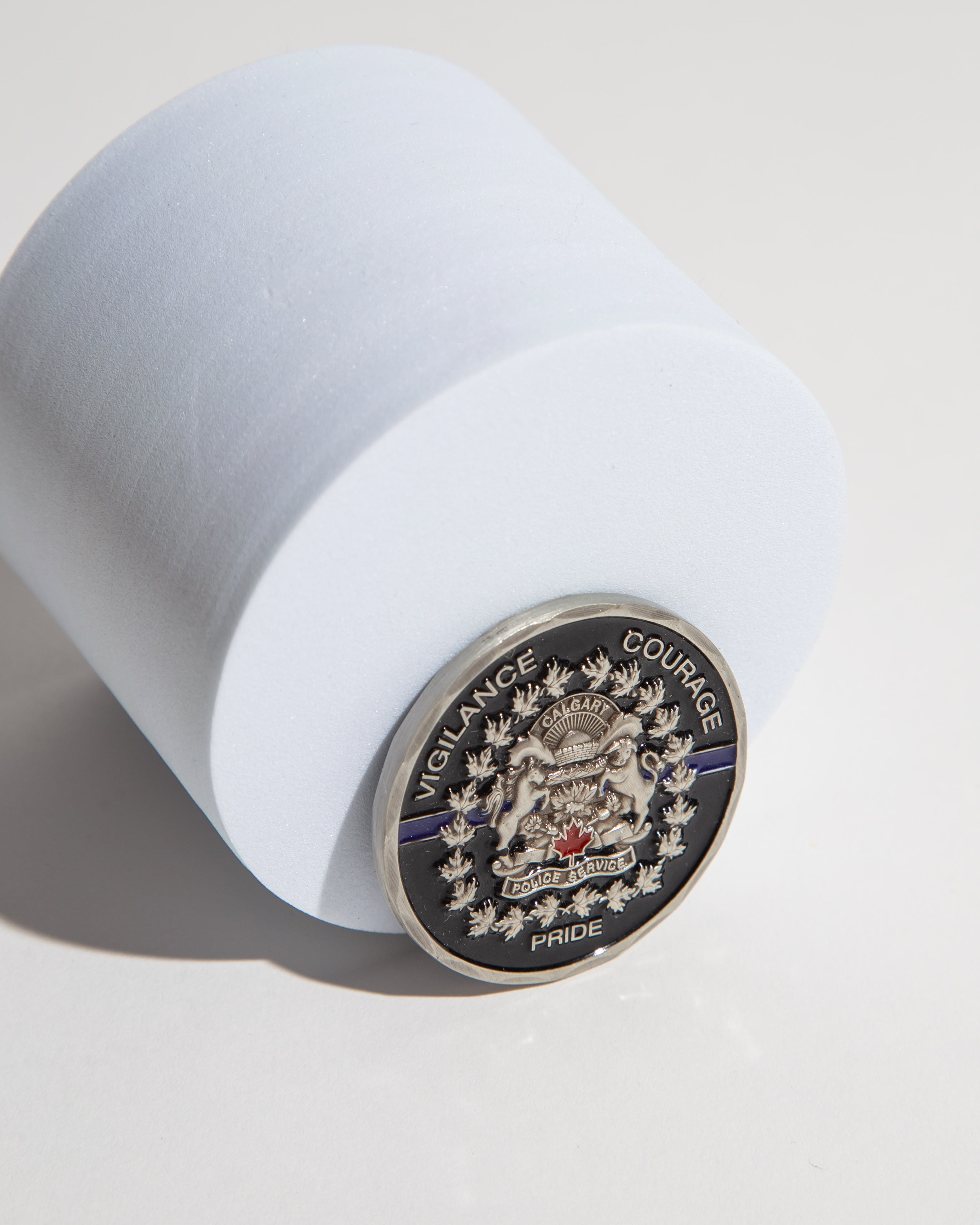 Calgary Police Service coin with emblem and words 'Vigilance Courage Pride' on a white surface.