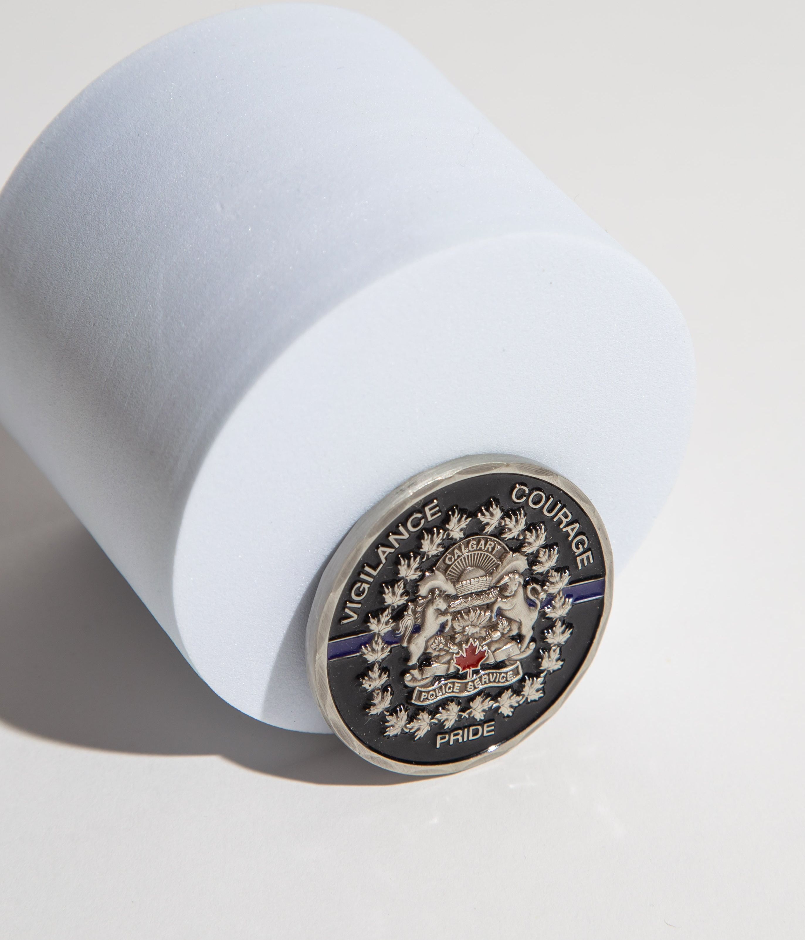 Calgary Police Service coin with emblem and words 'Vigilance Courage Pride' on a white surface.