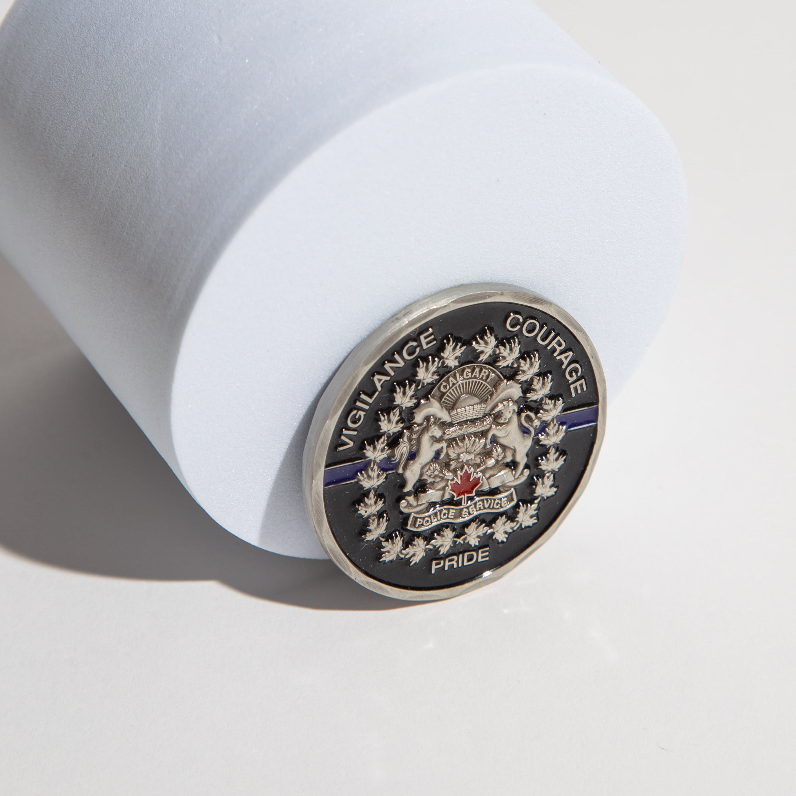 Calgary Police Service coin with emblem and words 'Vigilance Courage Pride' on a white surface.