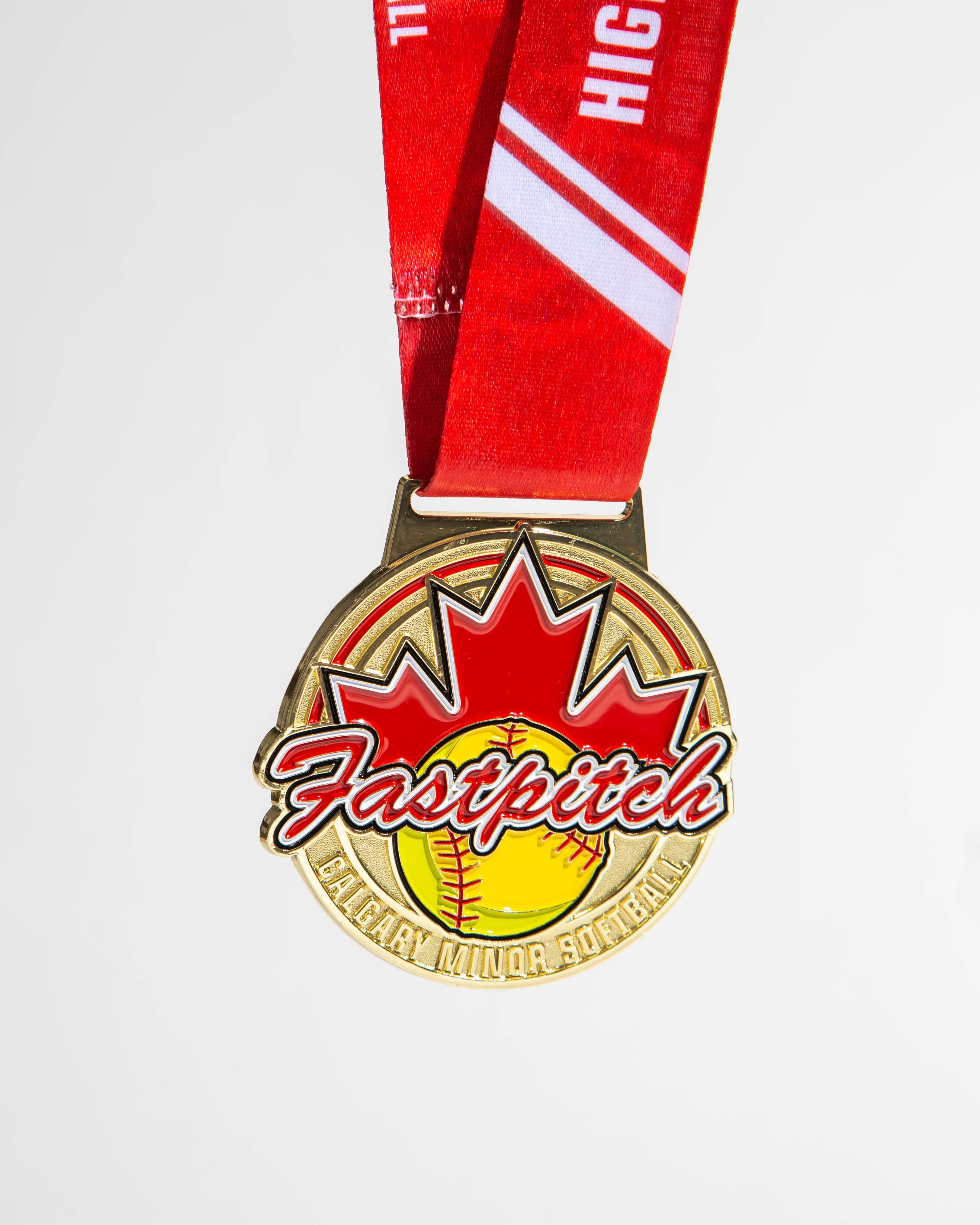 Gold softball medal with red maple leaf and custom Calgary Minor Softball branding, designed for fastpitch tournament champions.