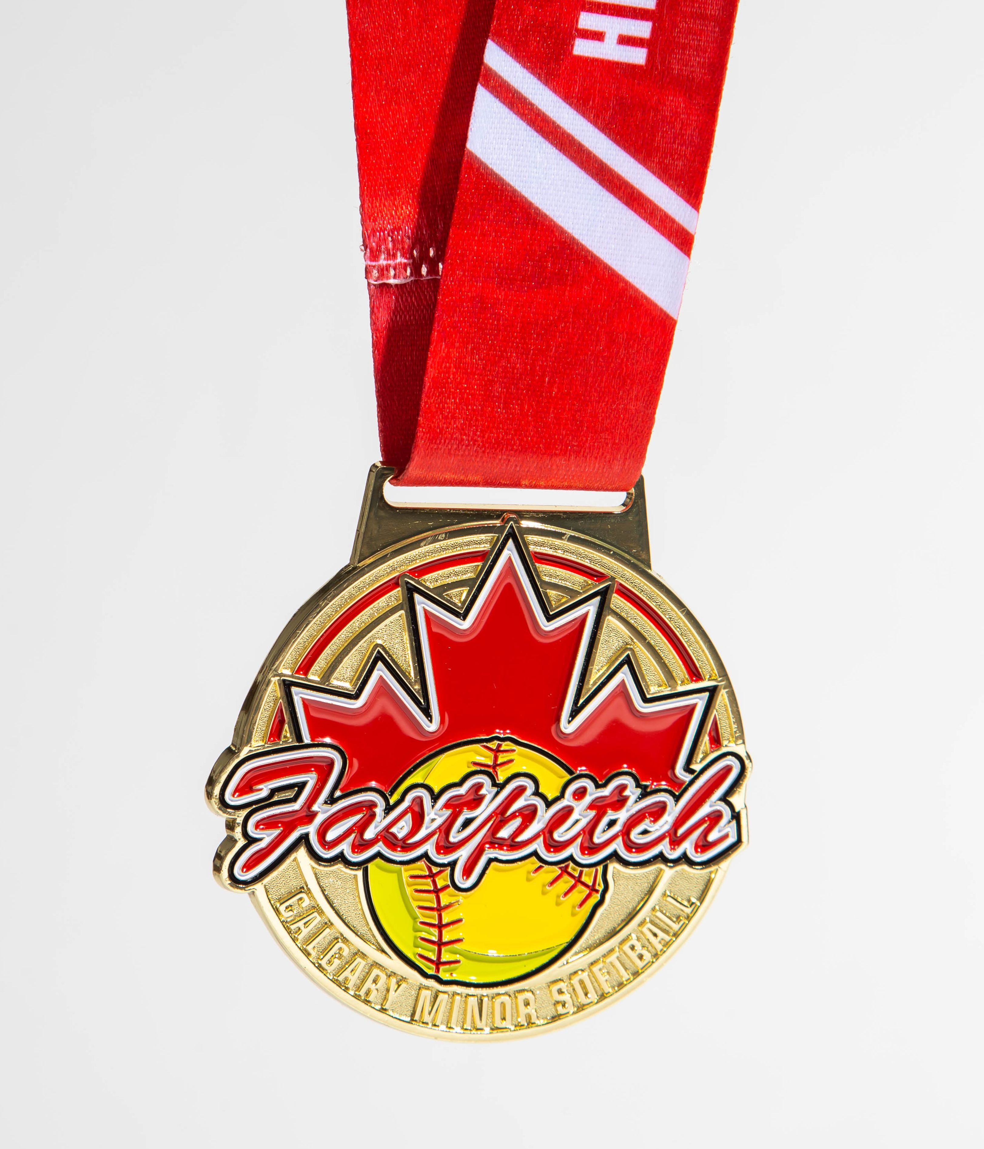 Gold softball medal with red maple leaf and custom Calgary Minor Softball branding, designed for fastpitch tournament champions.