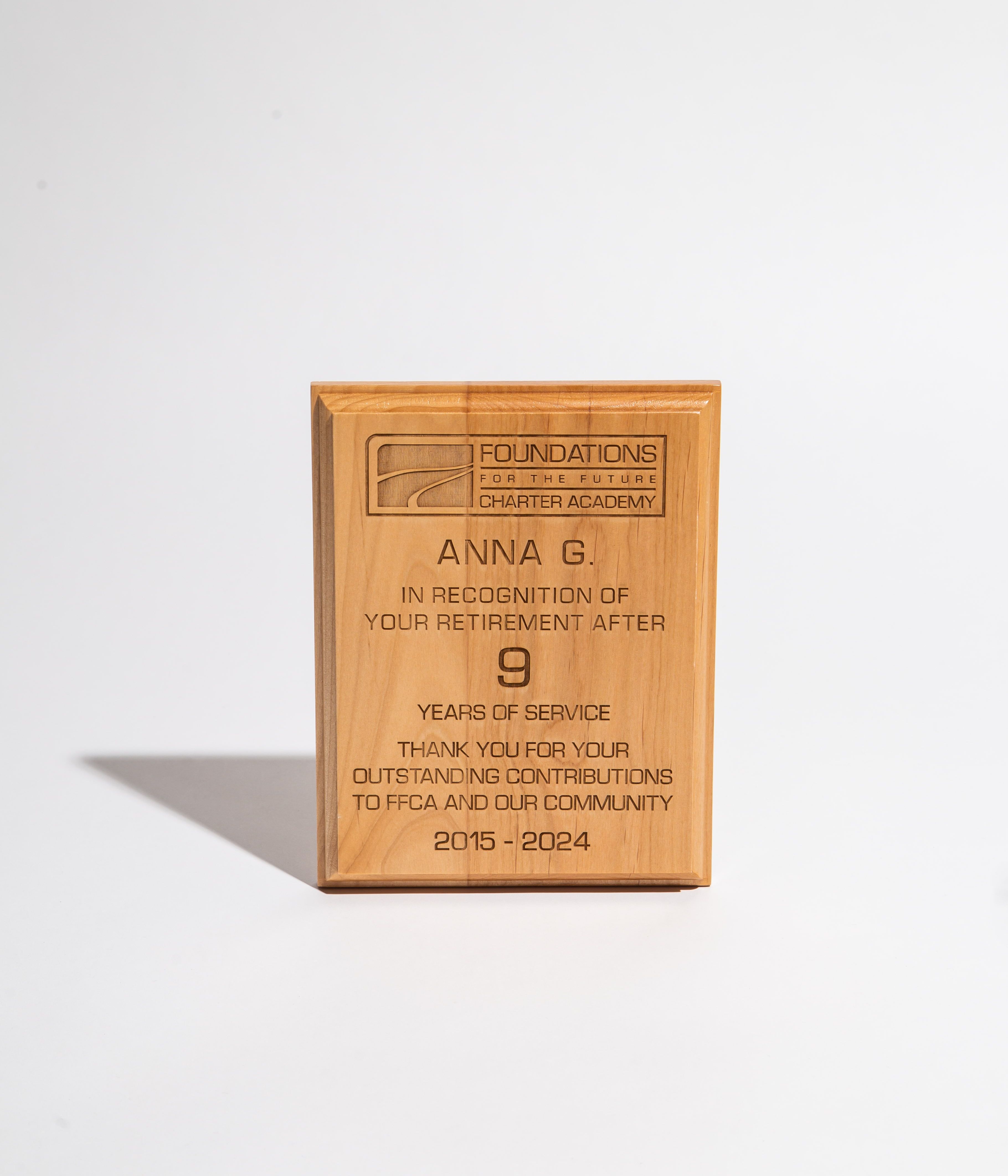 Wooden retirement plaque engraved with recognition message for nine years of service at a charter academy.