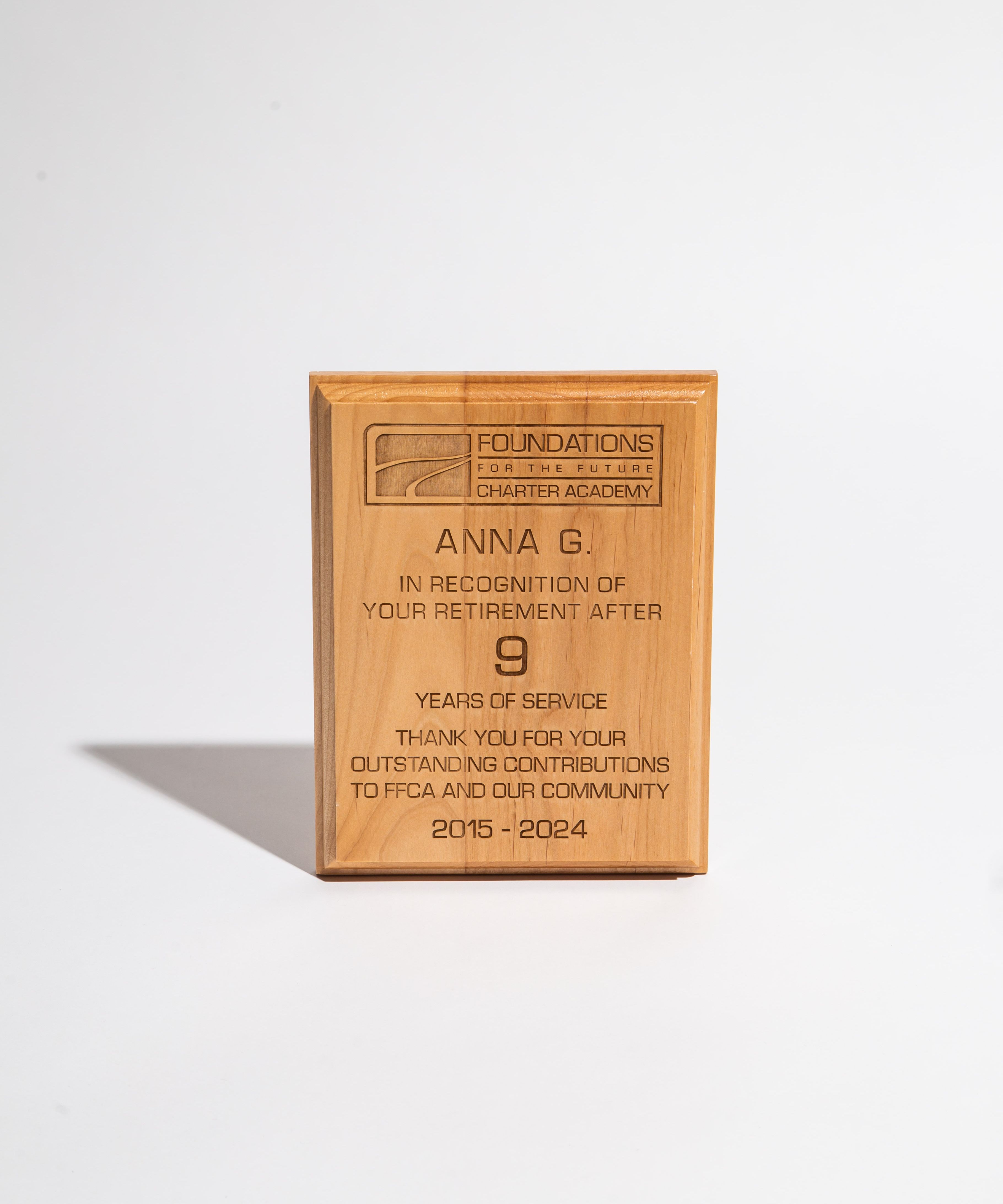 Wooden retirement plaque engraved with recognition message for nine years of service at a charter academy.