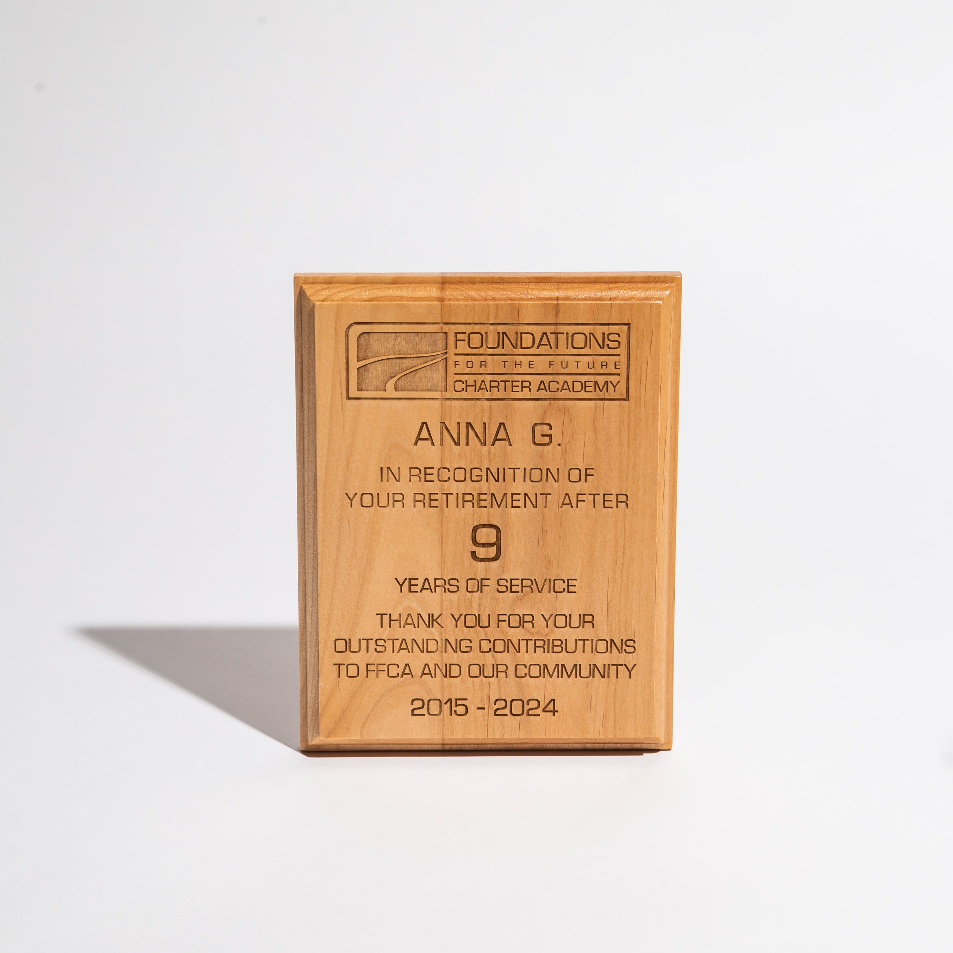 Wooden retirement plaque engraved with recognition message for nine years of service at a charter academy.