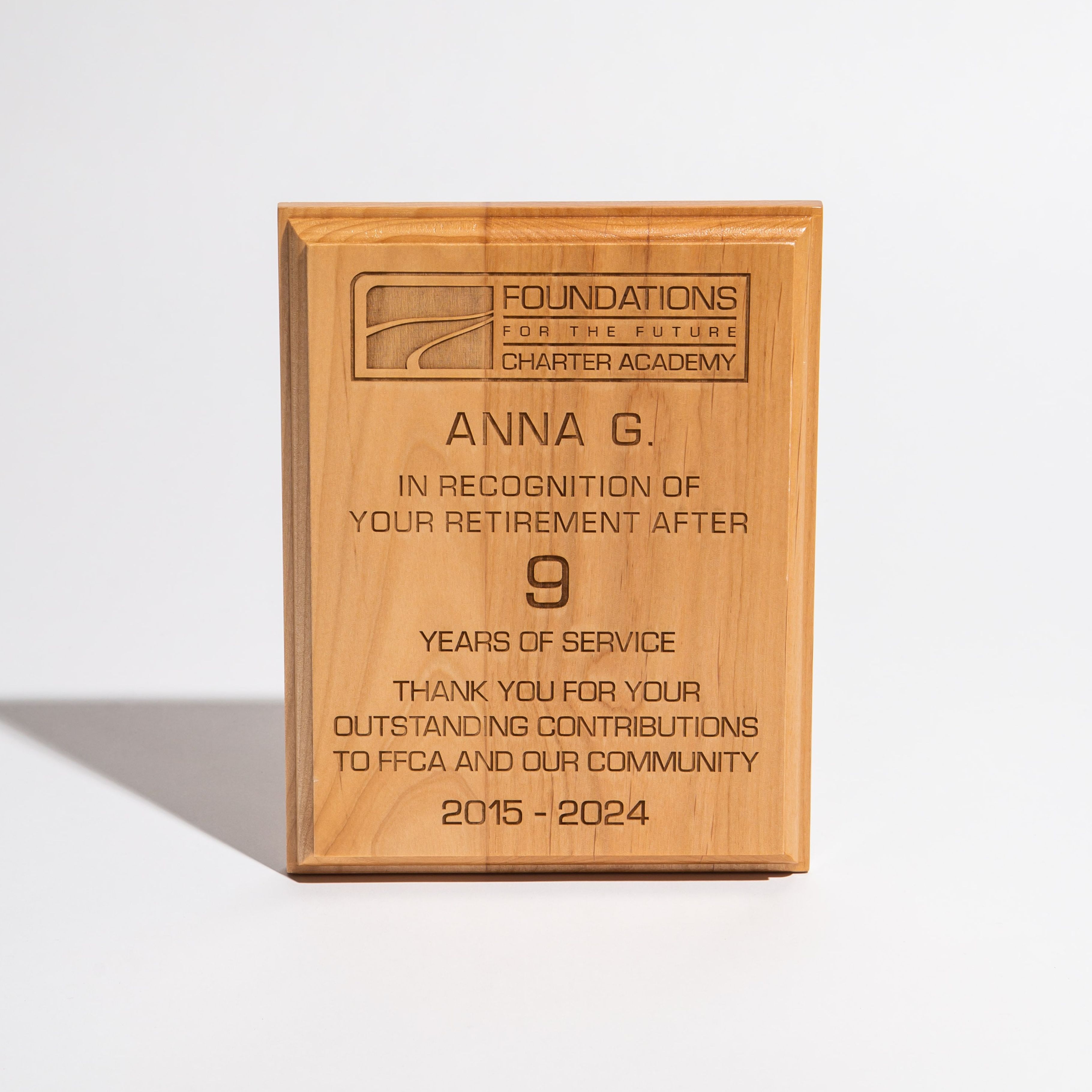 Wooden retirement plaque engraved with recognition message for nine years of service at a charter academy.